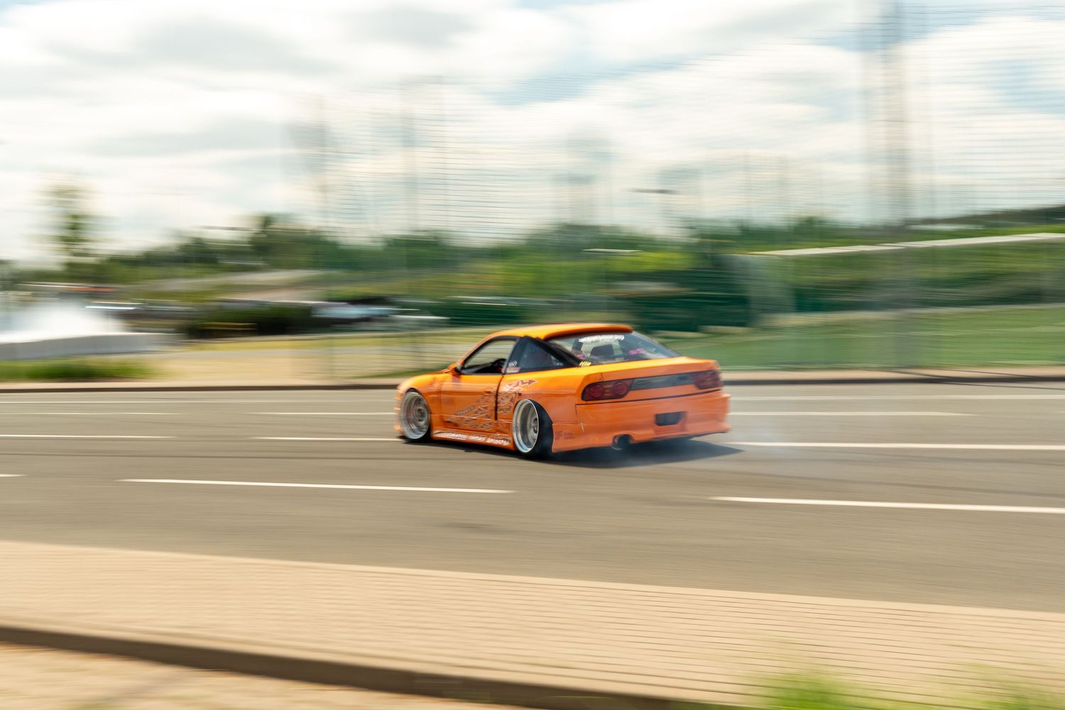 Orange modified sports car driving on track with motion blur effect.