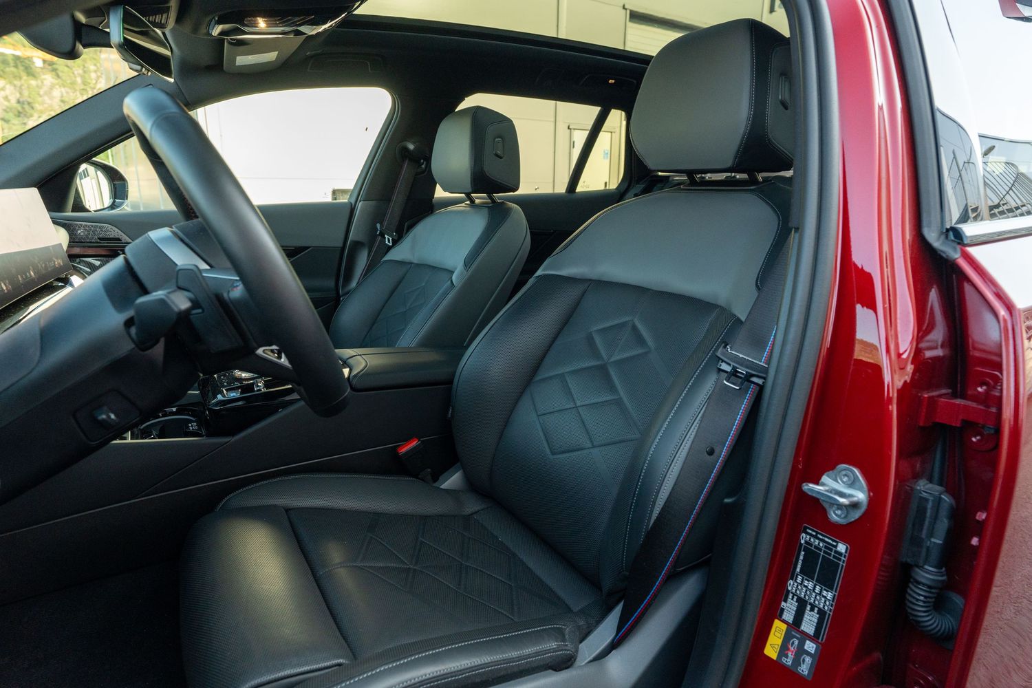 Red luxury car interior showing black leather seats and door panels with ambient lighting.