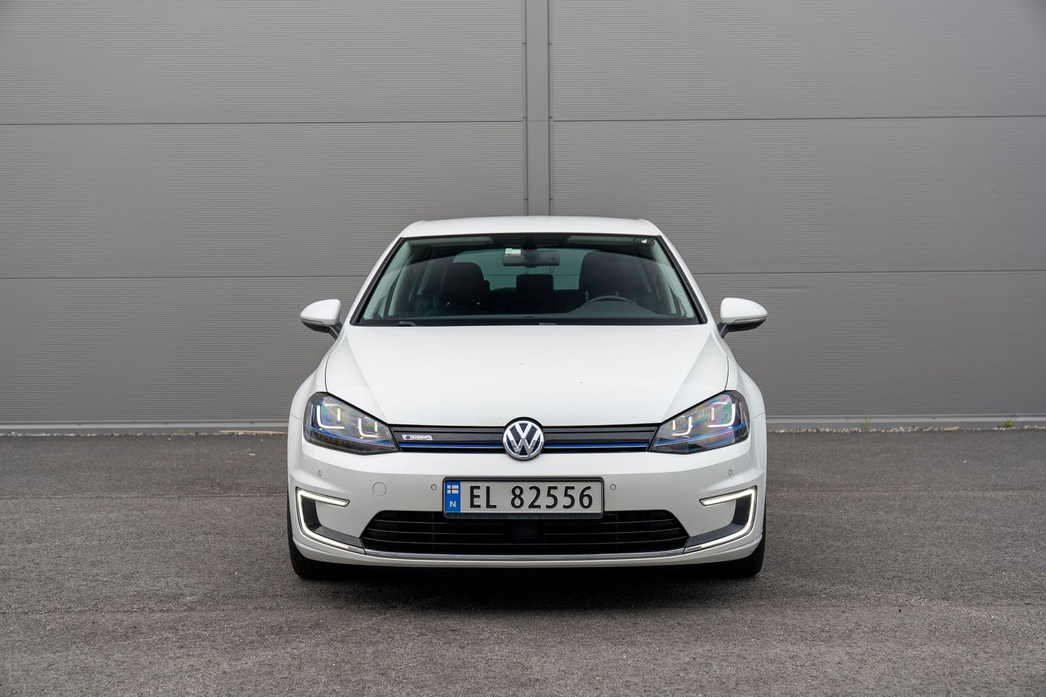 White parked vehicles seen from front headlight view showing modern automotive design details and lighting elements.