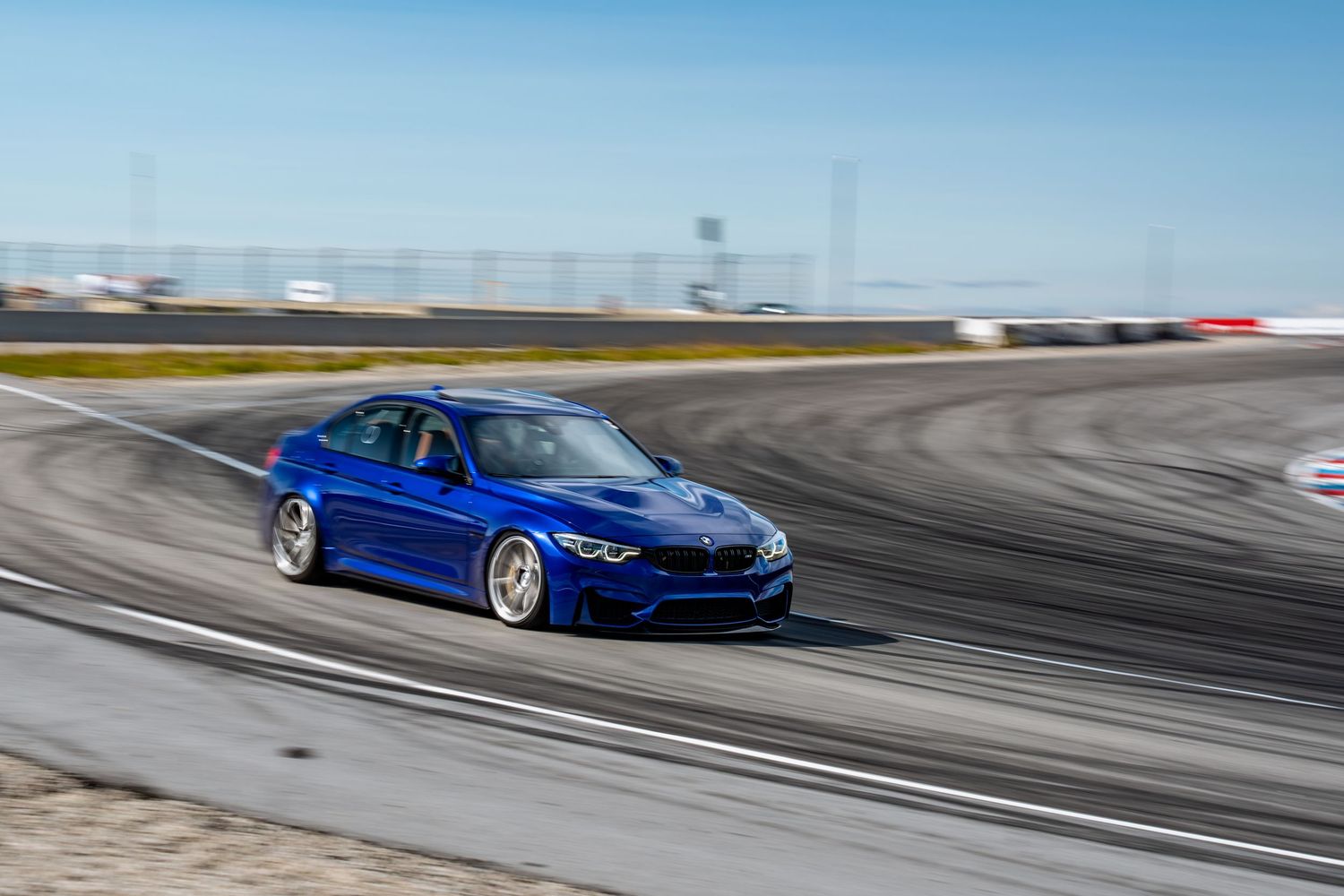 A blue BMW M4 sports car drifts on a racetrack leaving dramatic tire marks on the asphalt in multiple action shots.