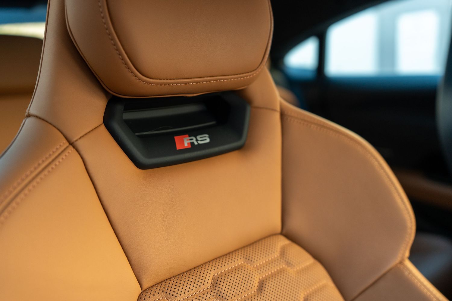 Luxurious tan leather sports seat with RS badge detail in an Audi vehicle interior.
