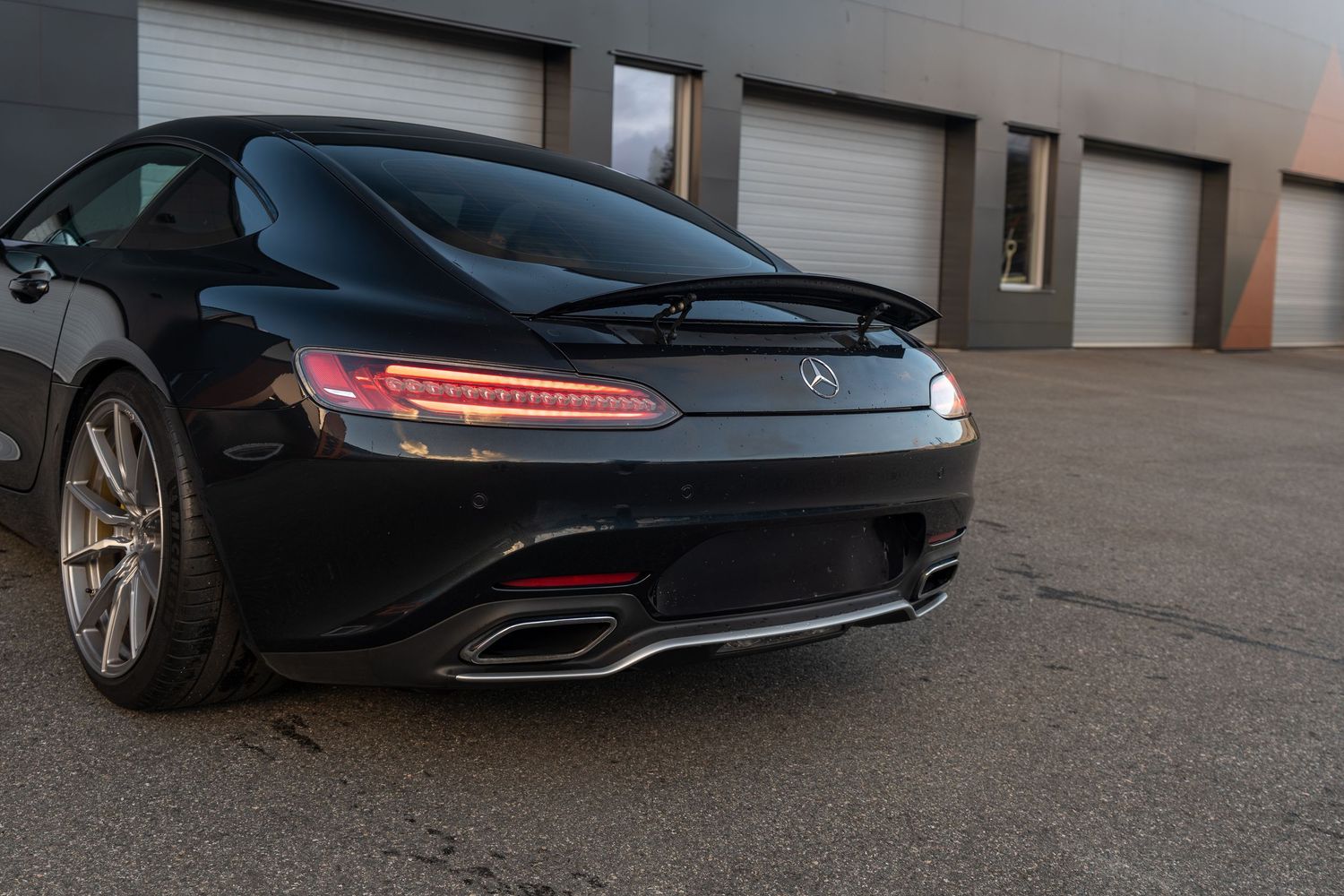 Close-up rear view of a black Mercedes-AMG GT showing its distinctive LED taillights and dual exhaust tips.