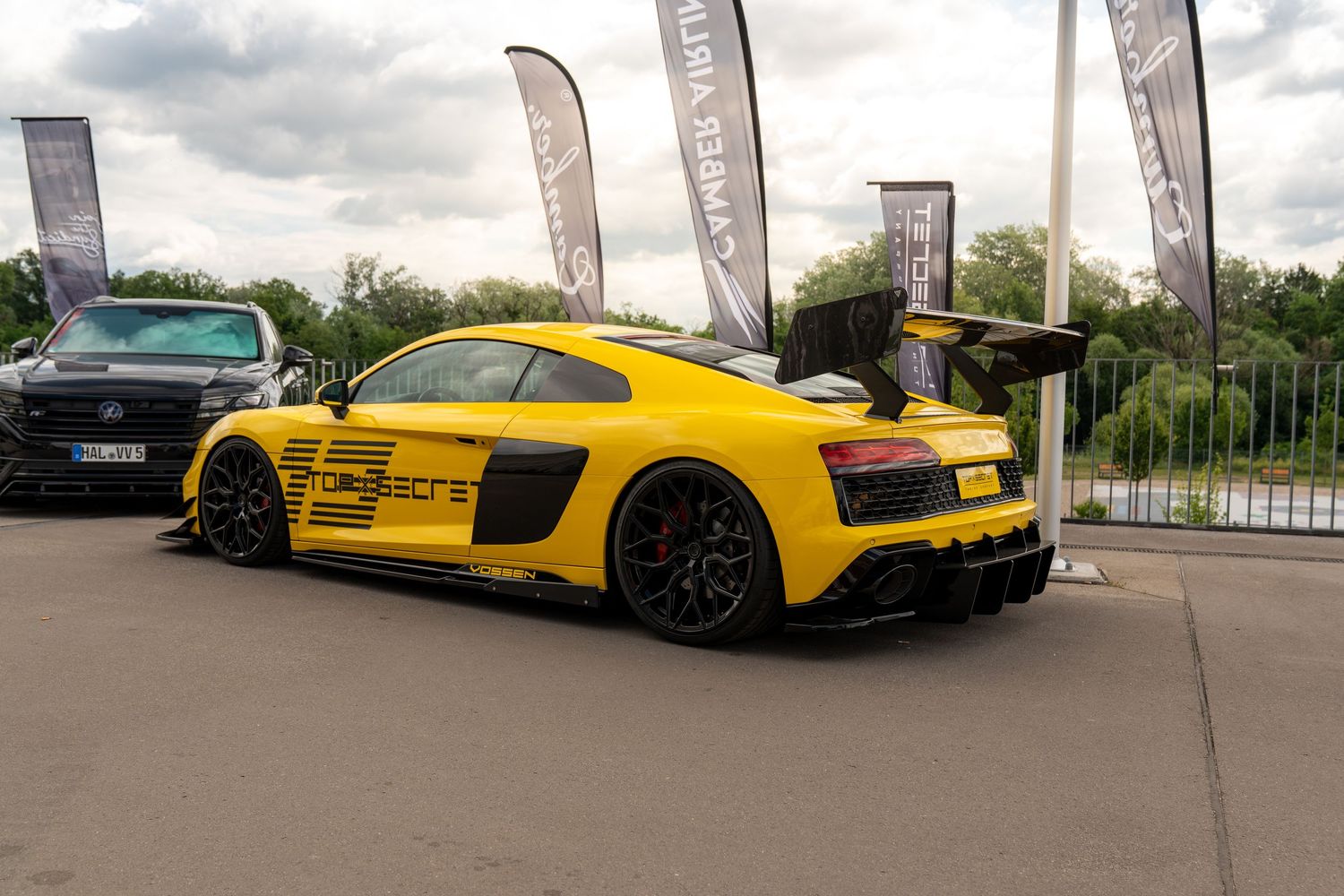 Yellow and silver supercars displayed at an outdoor automotive event.