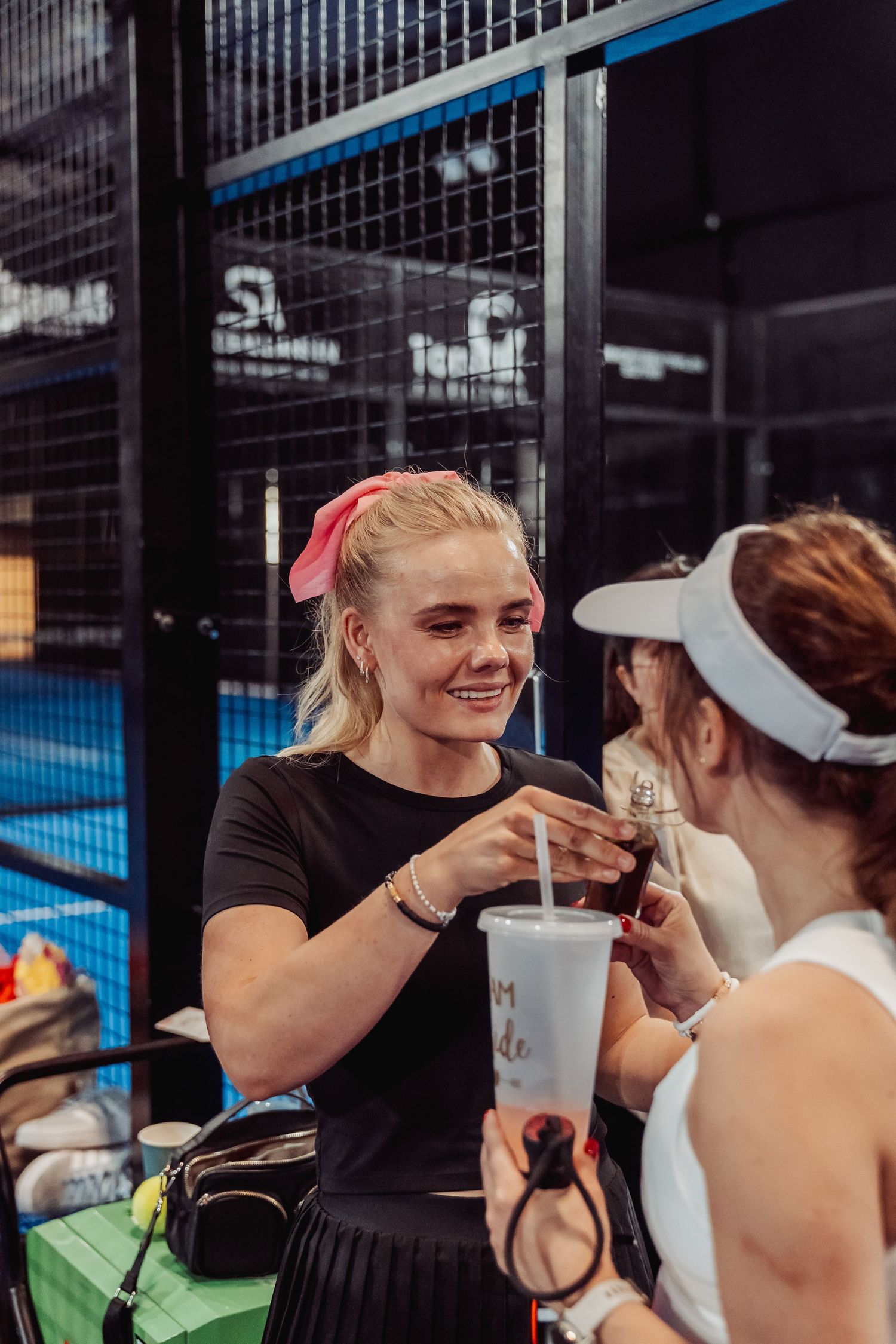 Players sharing drinks and refreshments during break at indoor tennis facility.