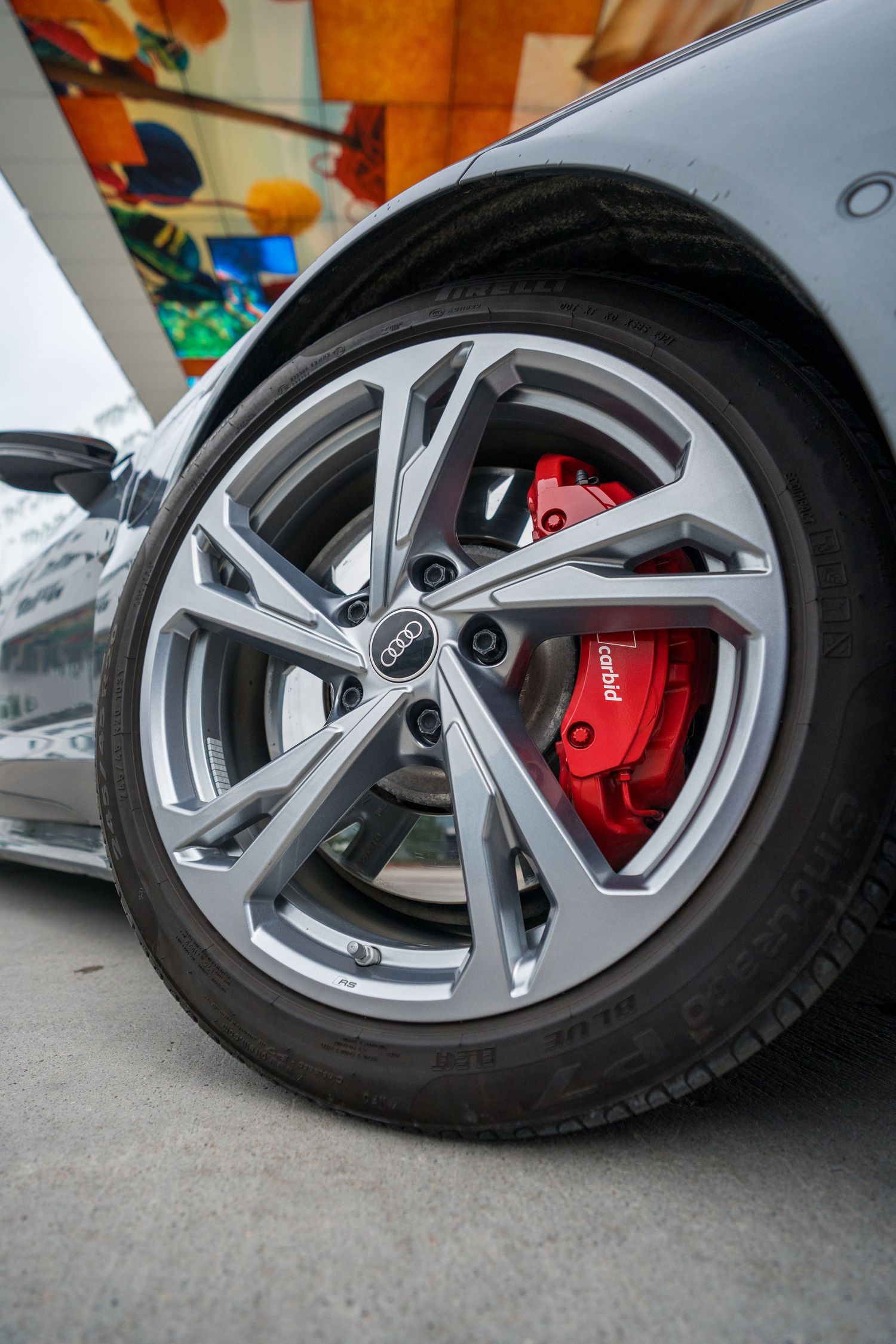 Close-up of a silver alloy wheel with red brake caliper on a luxury performance car.