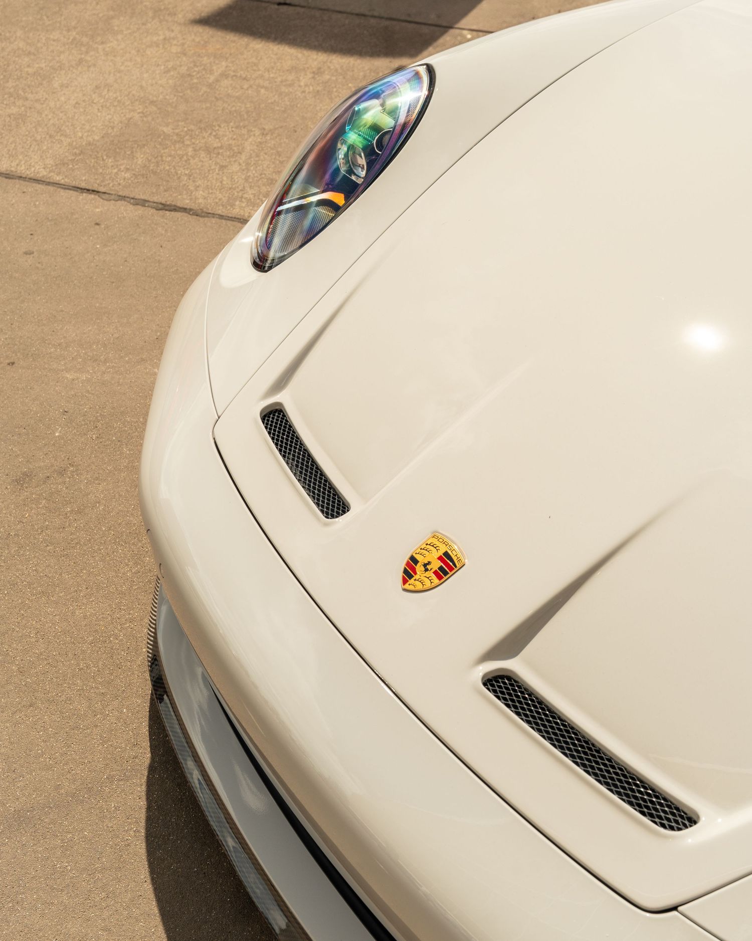 White Porsche sports car exterior with distinctive hood vents and Porsche badge.