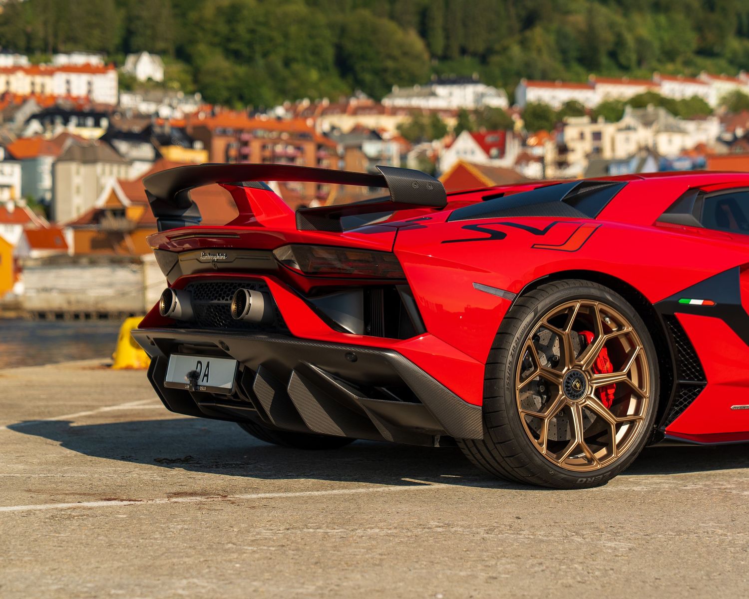 Rear quarter view of a red Lamborghini Aventador SVJ showing aerodynamic diffuser and wing.