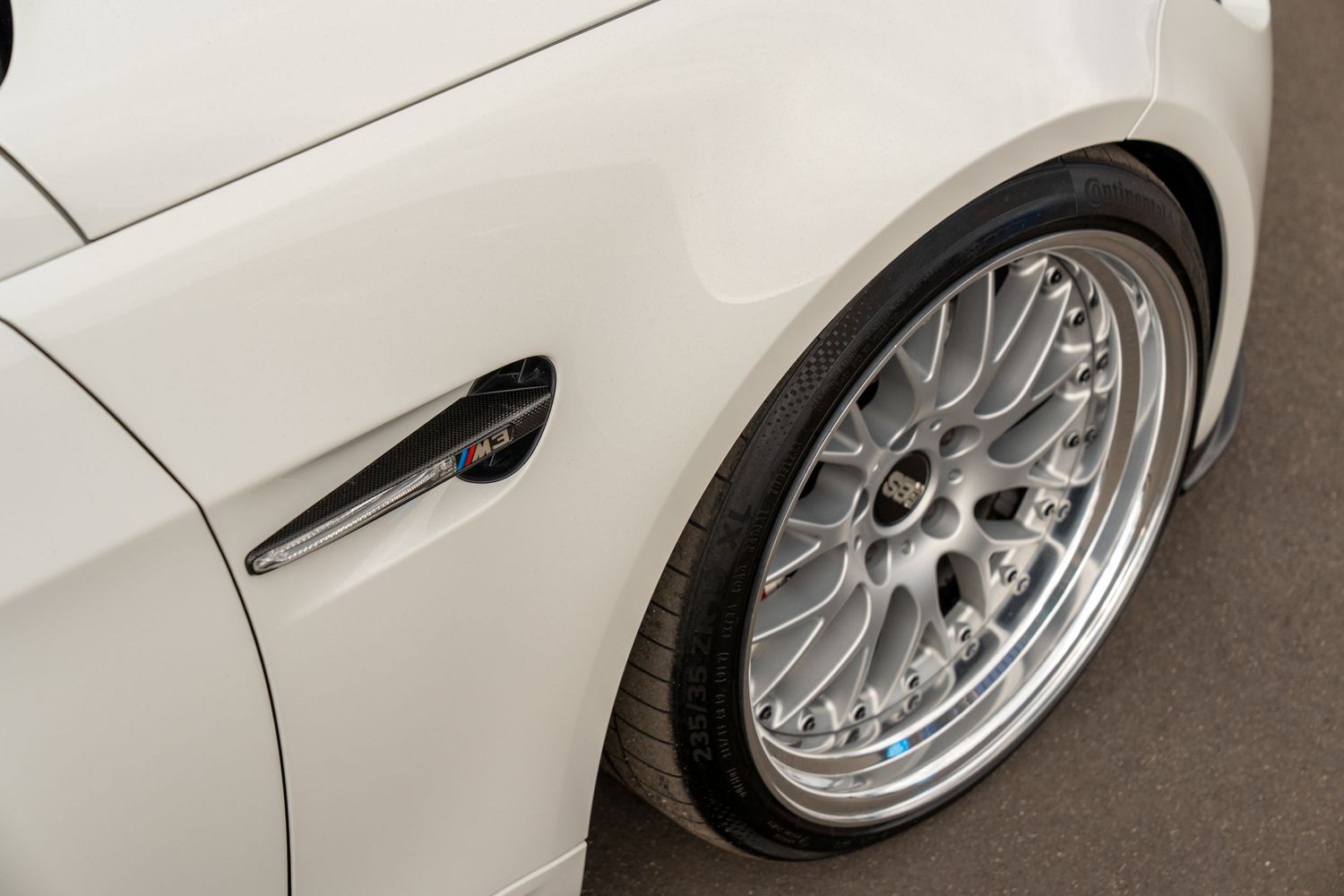 Close-up of a white car's wheel featuring a polished multi-spoke BBS rim design.