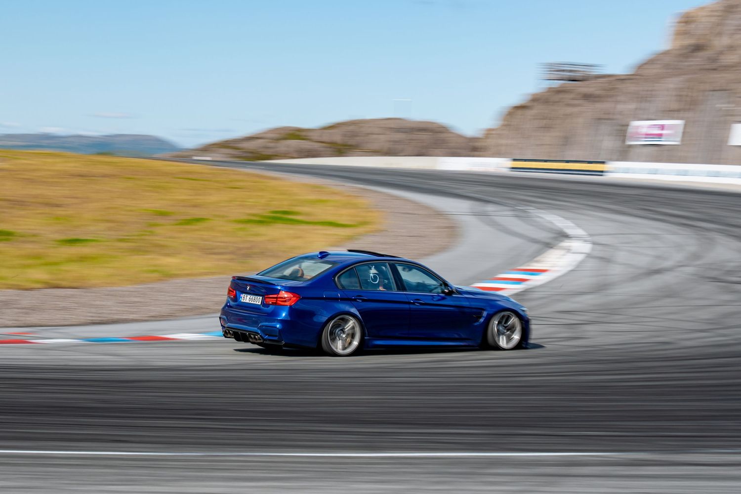 A collage of cars racing on a winding racetrack through varied terrain and weather conditions in dramatic action shots.