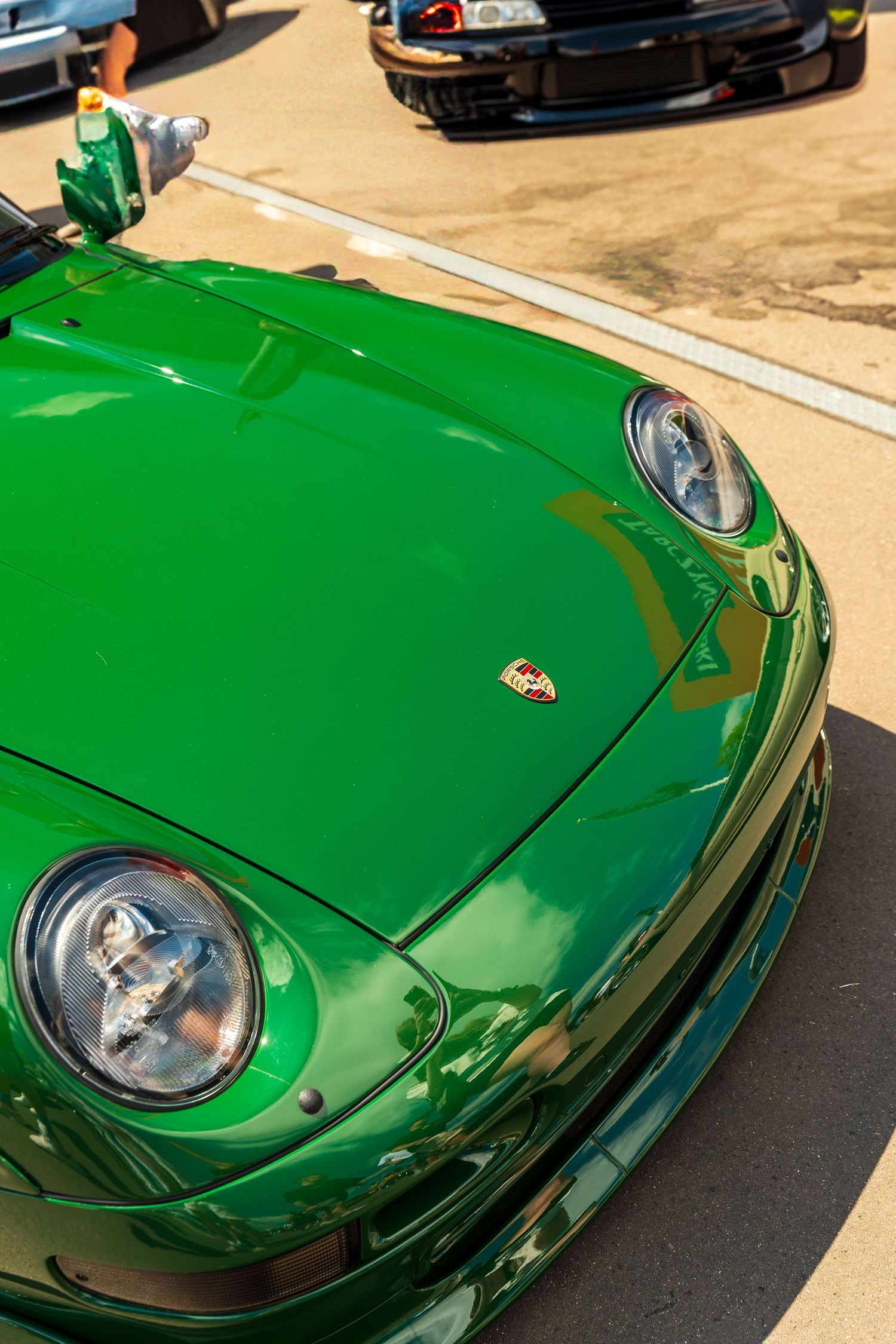 A bright green Porsche 911 with round headlights and custom modifications shown at a car meet.