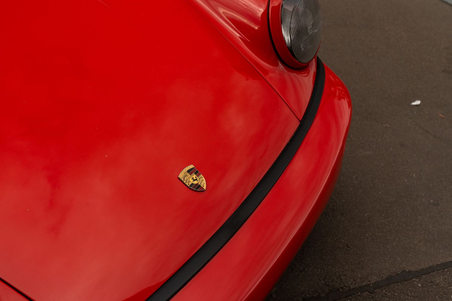 Detail shot of Ferrari emblem on glossy red paintwork.