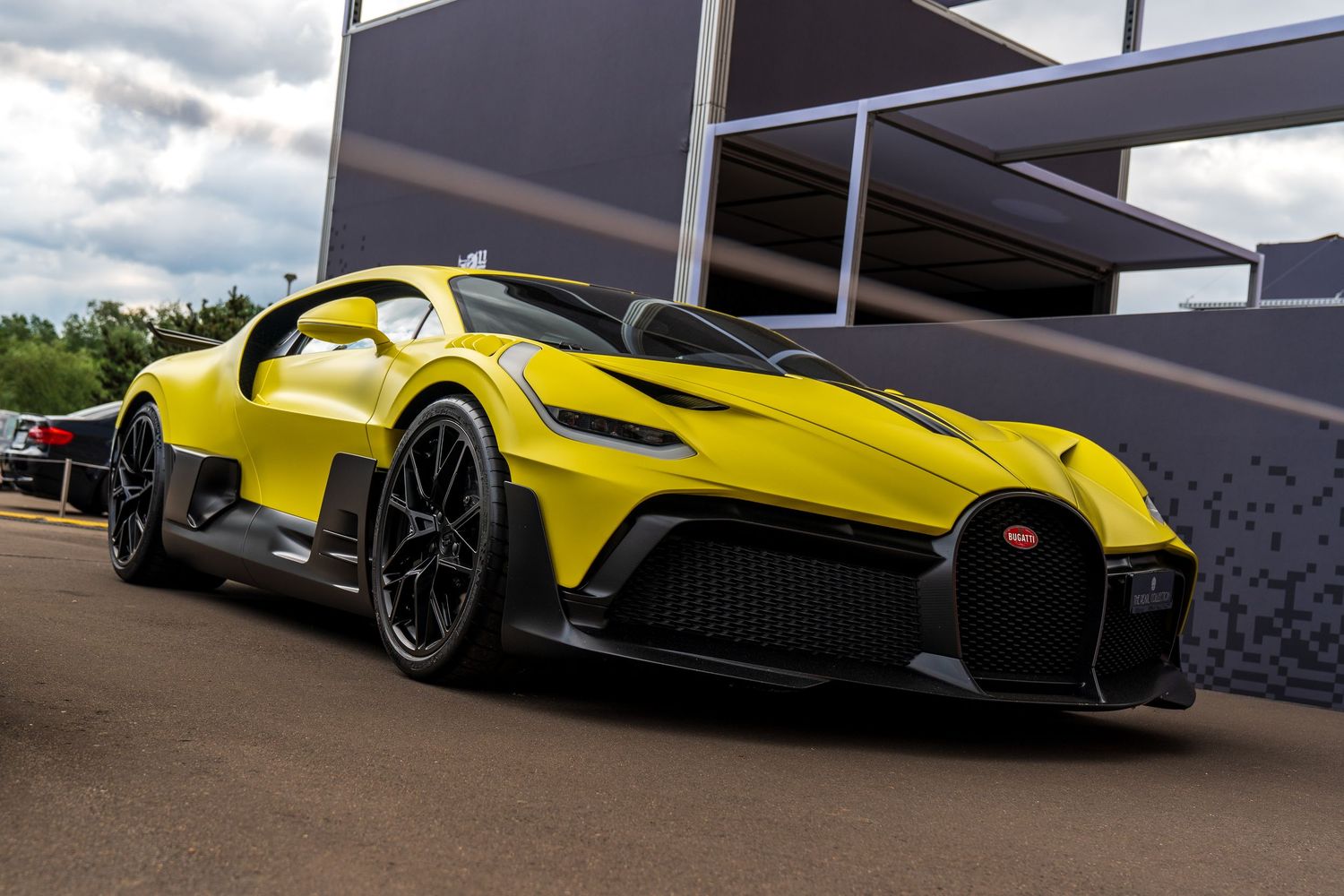 Striking yellow Bugatti Bolide hypercar with aggressive aerodynamics on display at an outdoor event.