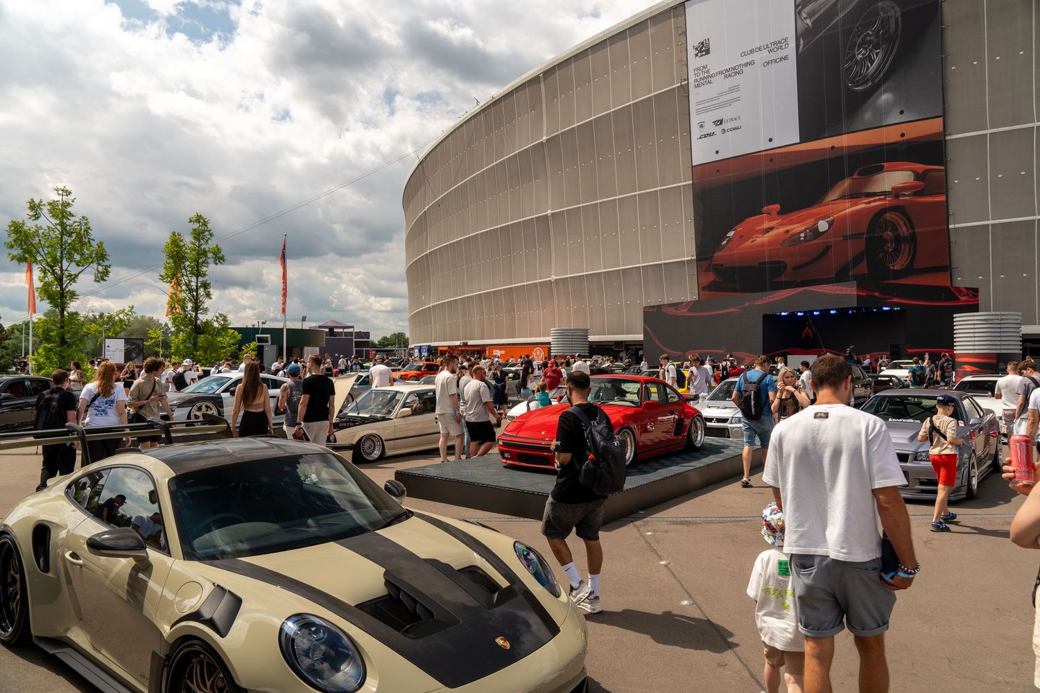 Modern Porsche sports cars displayed at an outdoor automotive event with crowd.