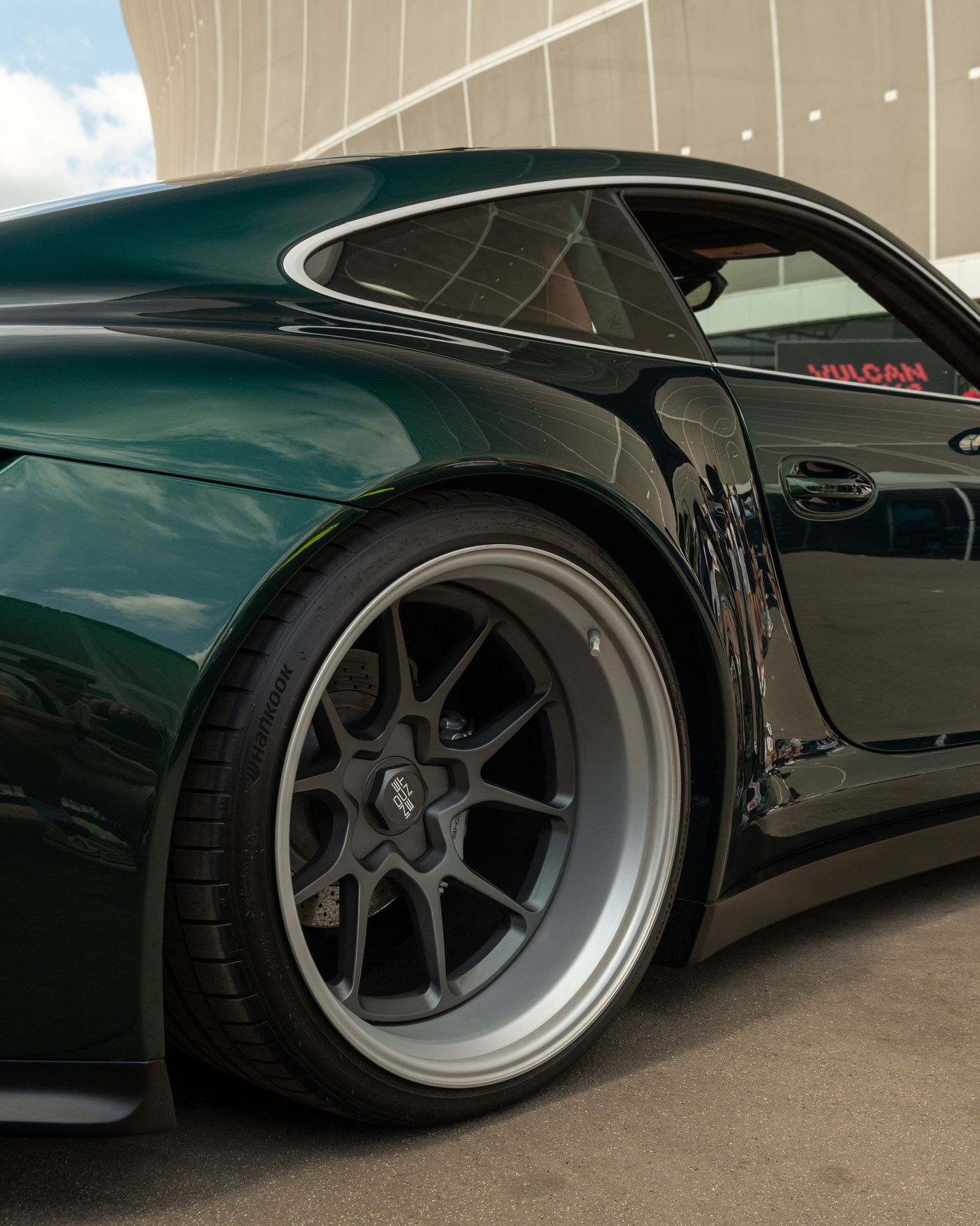 Dark green Porsche 911 showing aggressive wheel fitment and wide body styling.