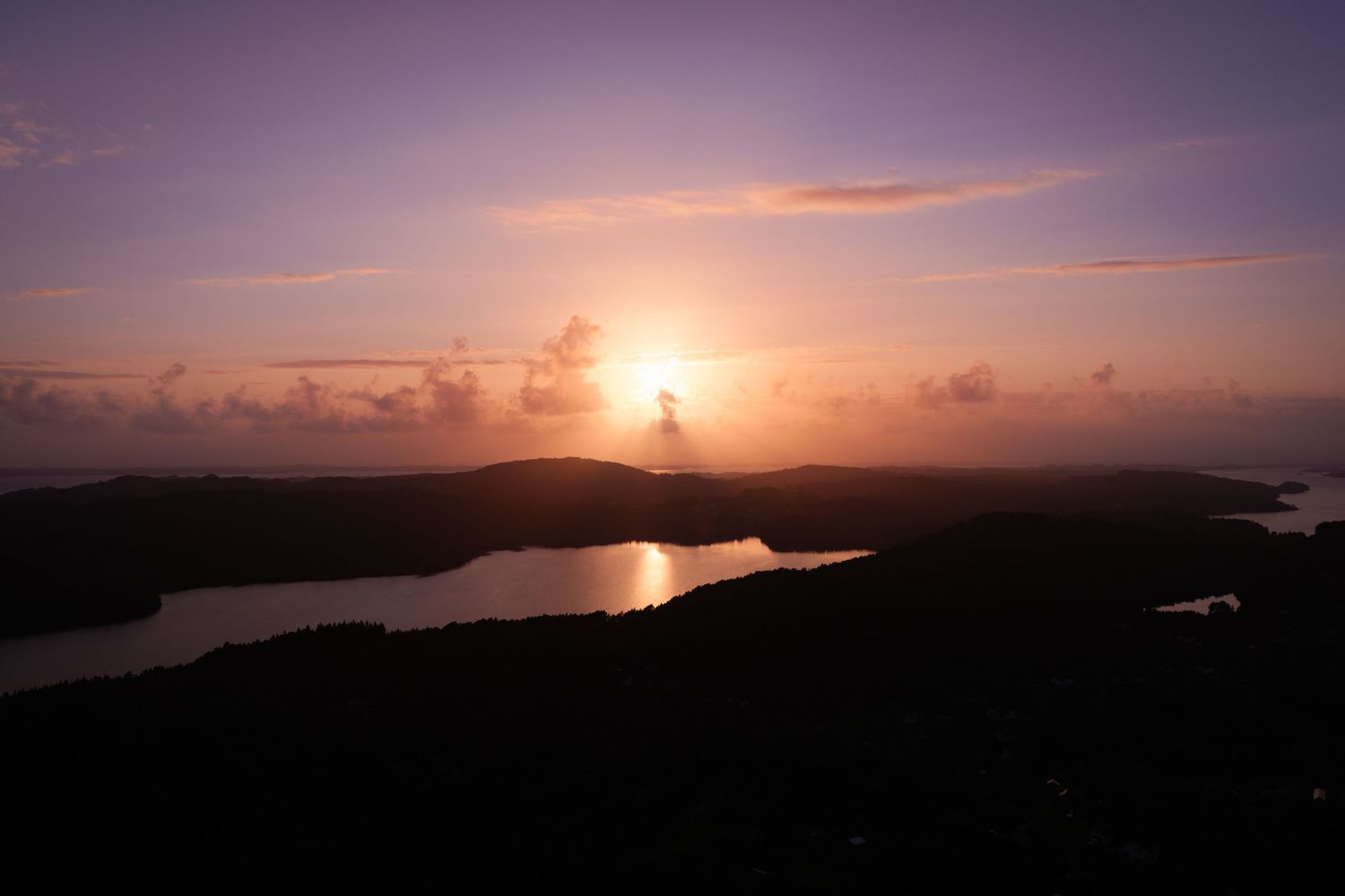 Stunning aerial sunset view over tropical islands with glowing orange sky reflecting on calm ocean waters.
