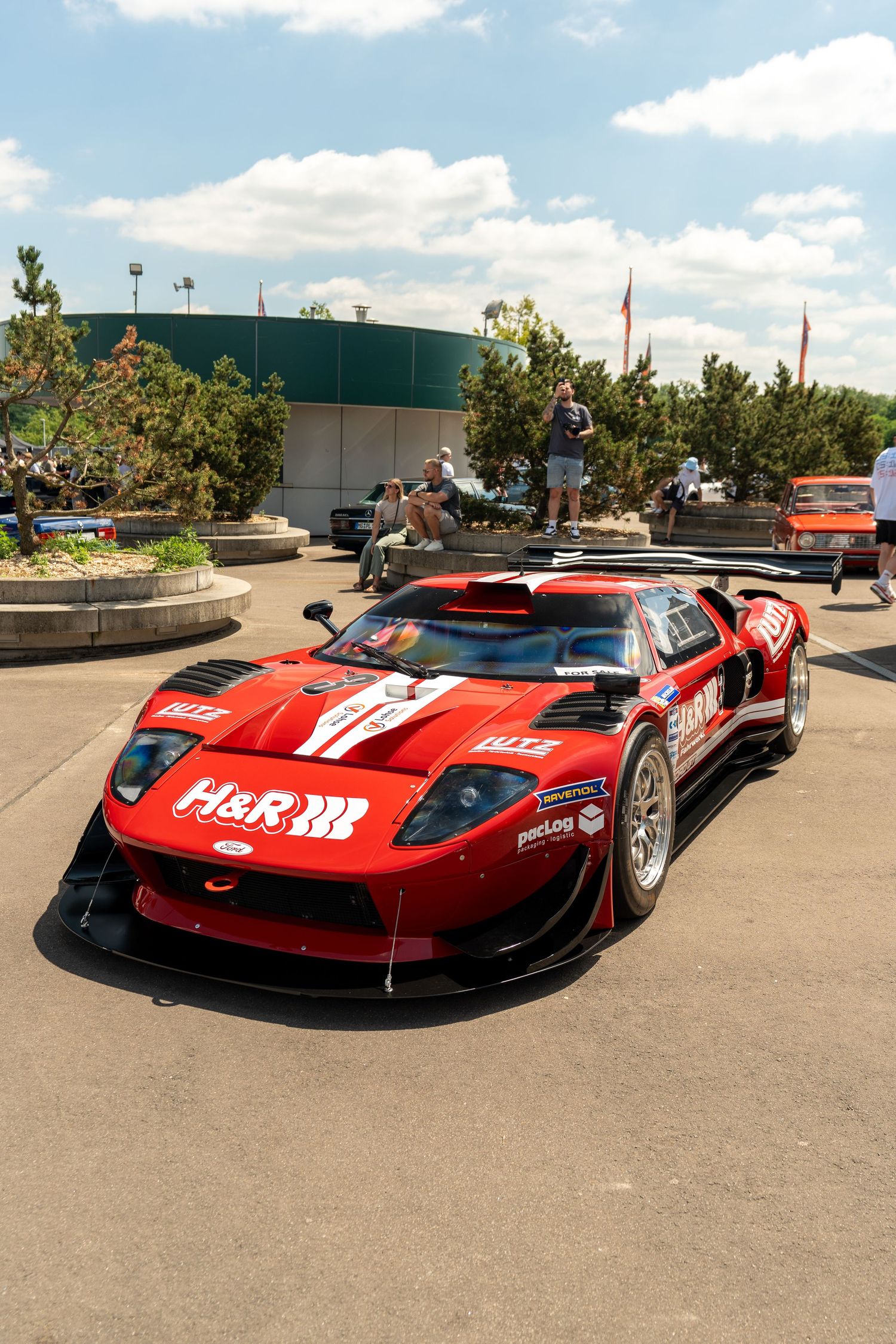 Red Ferrari race car with H&R branding displayed in parking area.