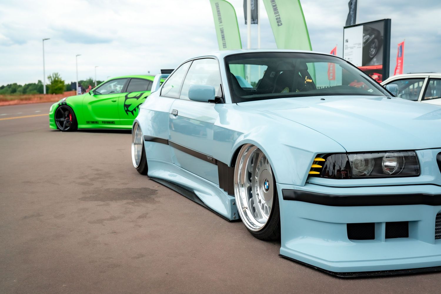 Row of modified vintage cars featuring extreme lowered suspension and custom bodywork.
