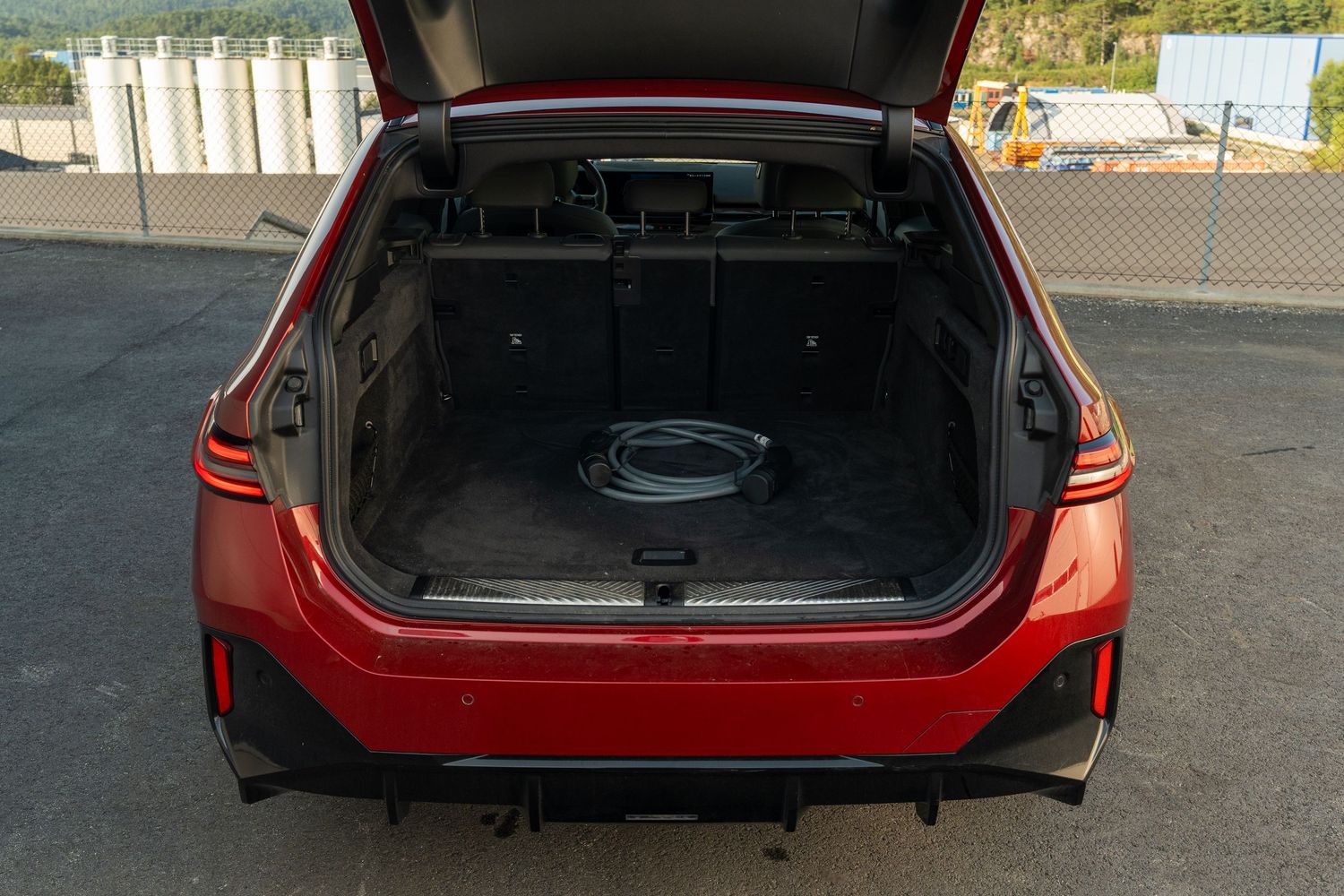 Open trunk space of a red luxury vehicle showing spacious cargo area.