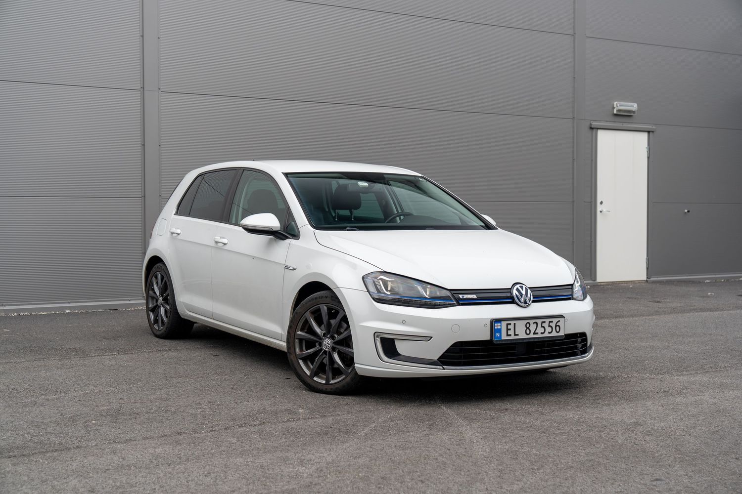 Four white Volkswagen Golf GTI sports cars lined up against a gray wall showcasing their sleek design and styling.