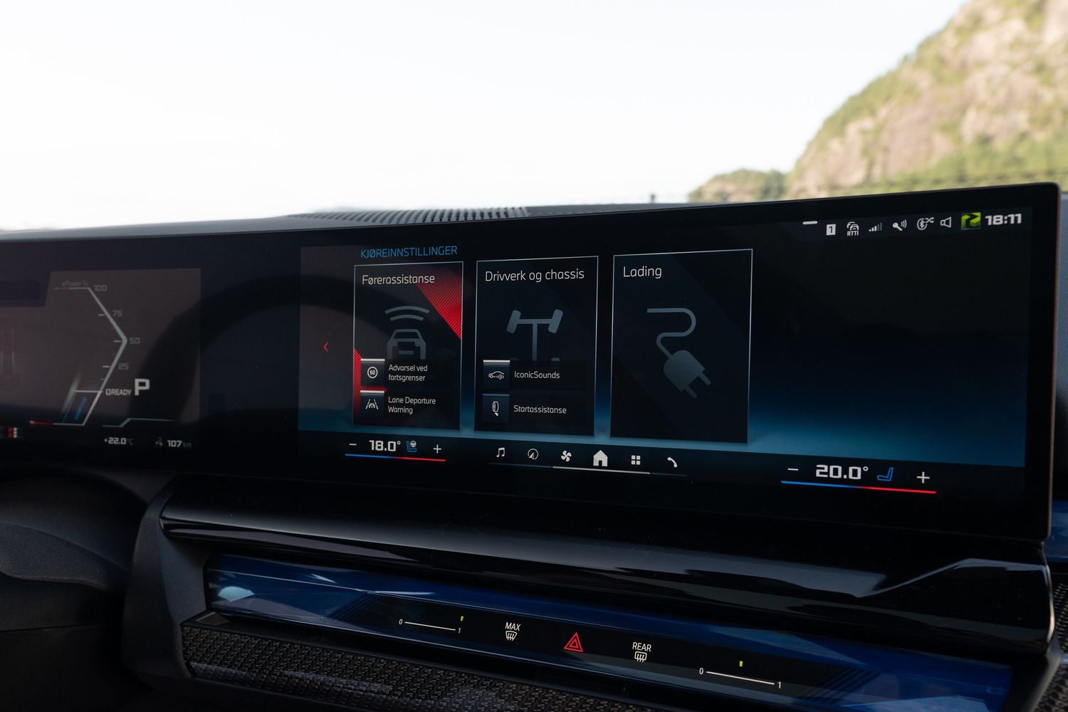 BMW's curved display interface showing multimedia and vehicle settings in blue lighting.