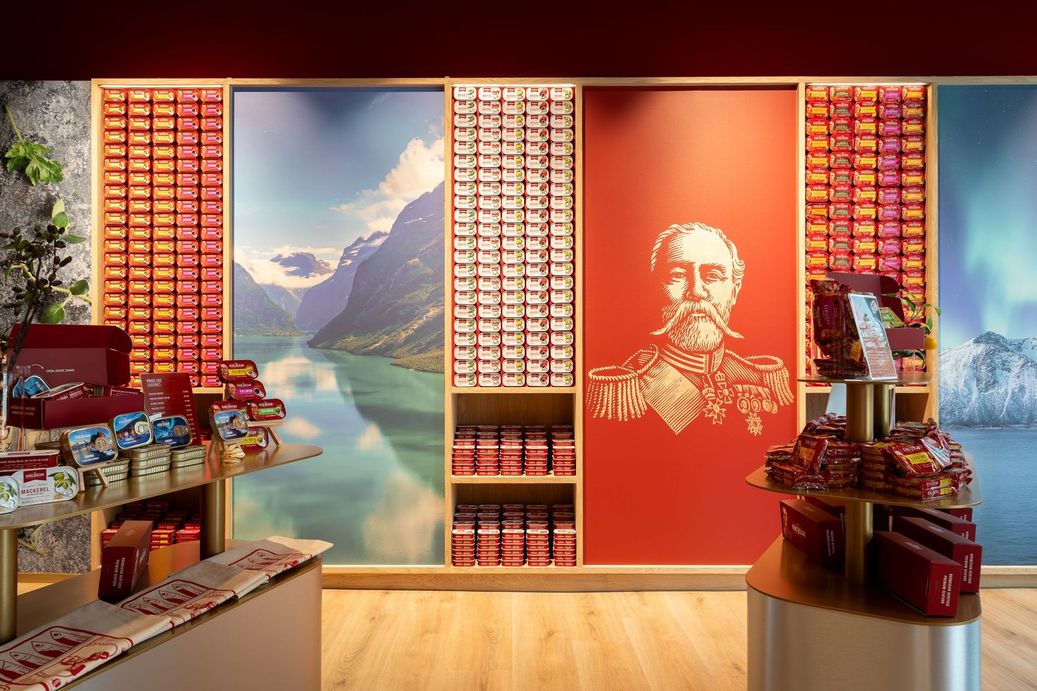 Boutique interior with red shelves of packaged goods, a mountain lake mural and a red wall graphic of a uniformed man with a mustache.
