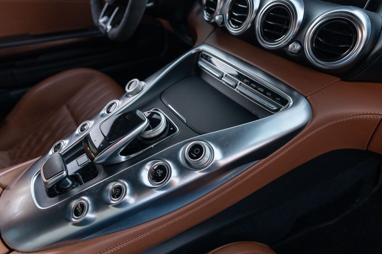 Close-up of Mercedes-AMG gear selector and console controls in metallic finish.