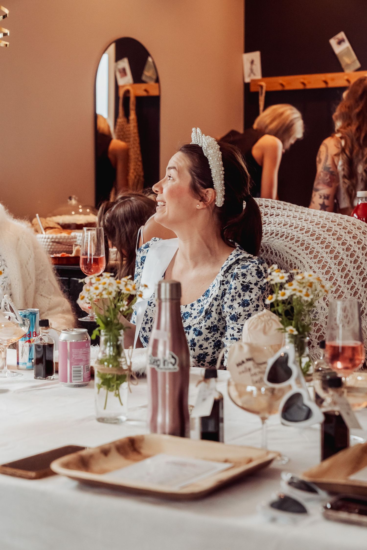 A wedding reception table decorated with floral centerpieces, wine bottles, and place settings at an elegant indoor venue.
