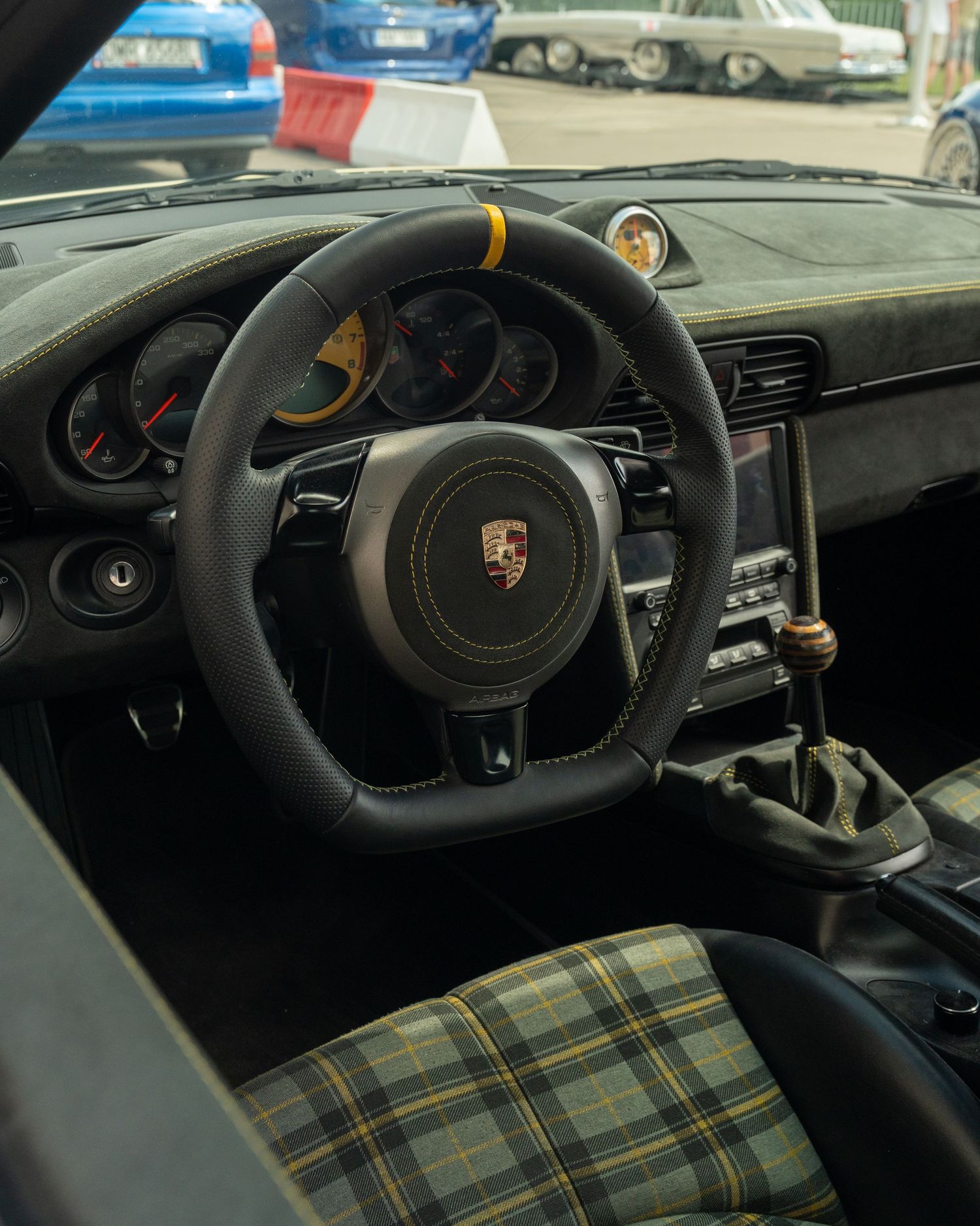 Black leather steering wheel and dashboard interior of a Porsche sports car.