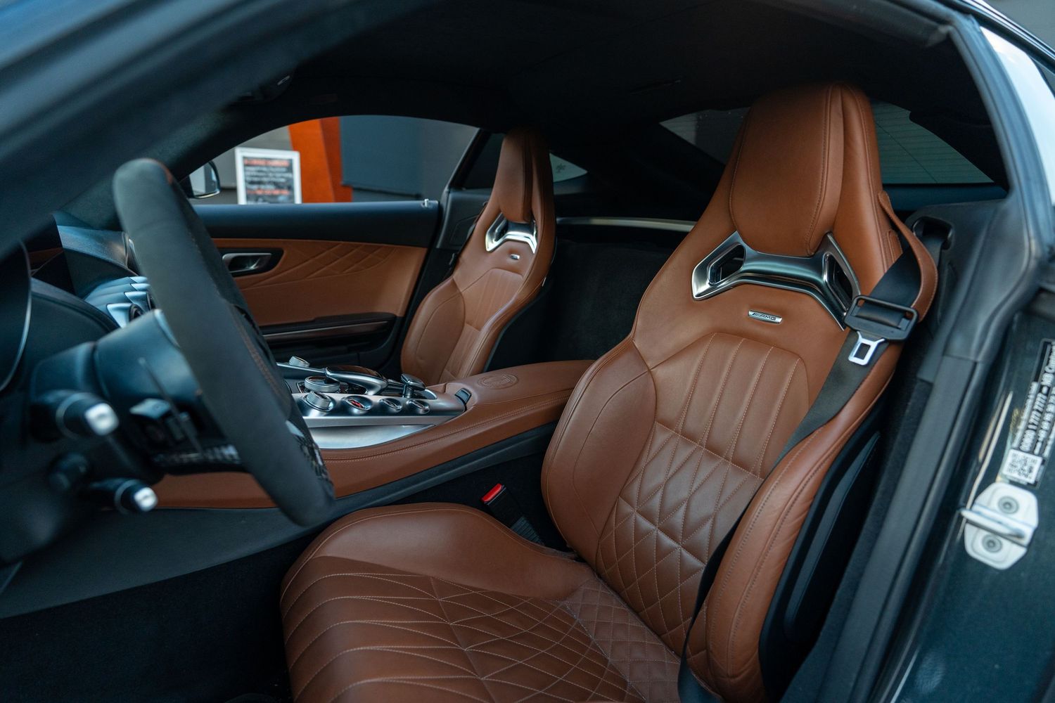 Luxury car interior featuring premium brown leather seats with diamond stitched pattern and modern dashboard controls.