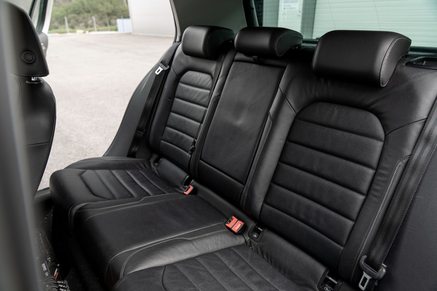 Spacious black leather back seat interior of a luxury car showing comfortable seating and safety features.