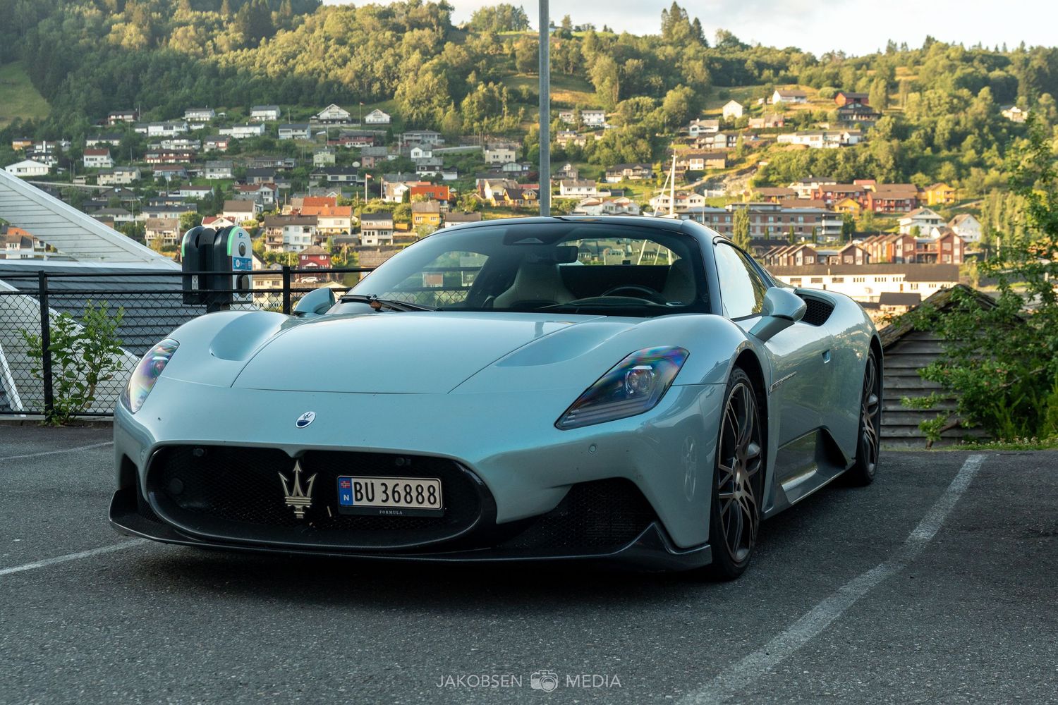 High-end supercars lined up in a scenic parking area with mountain views.