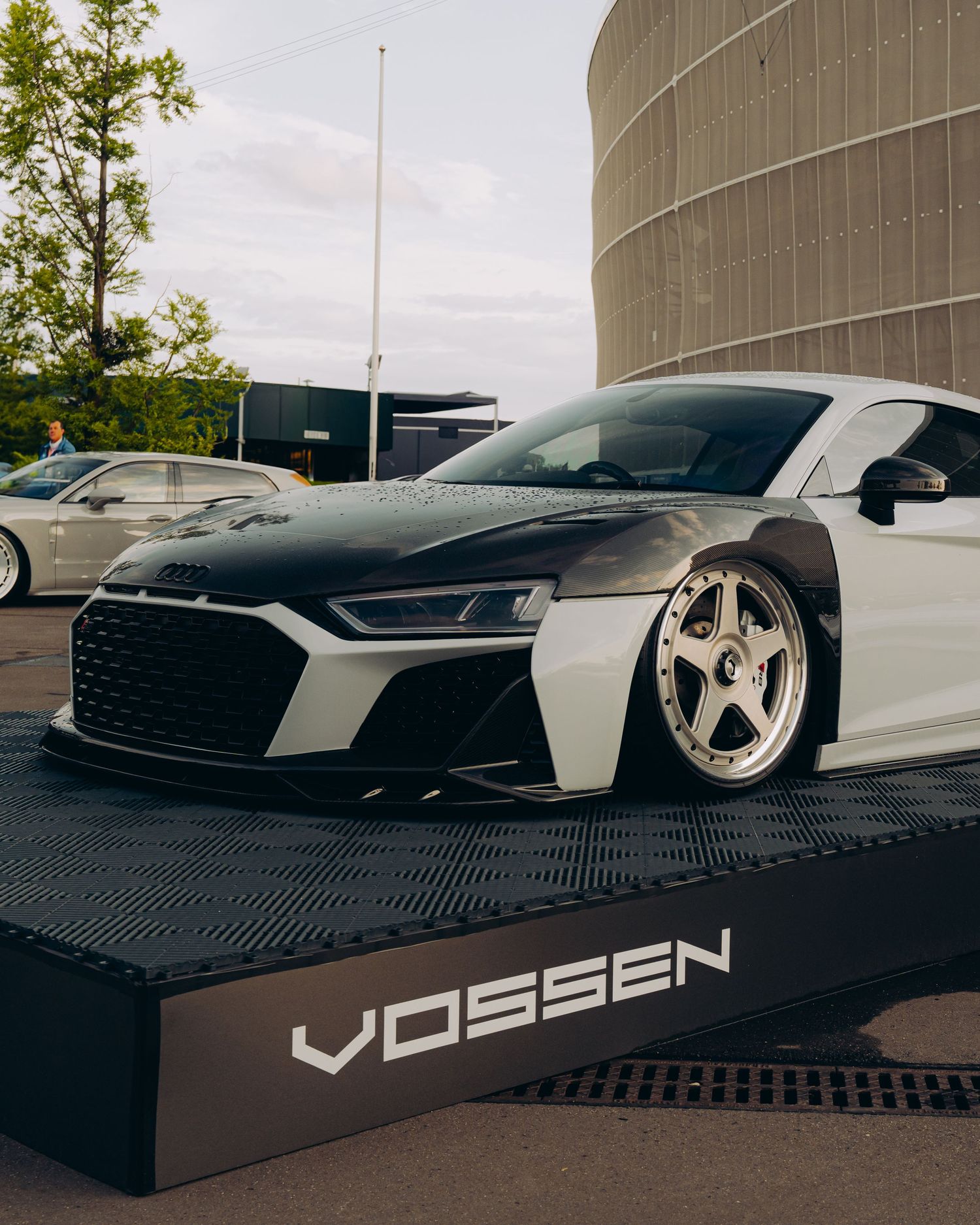 A customized white Audi R8 with Vossen wheels sits on display at an outdoor car show.