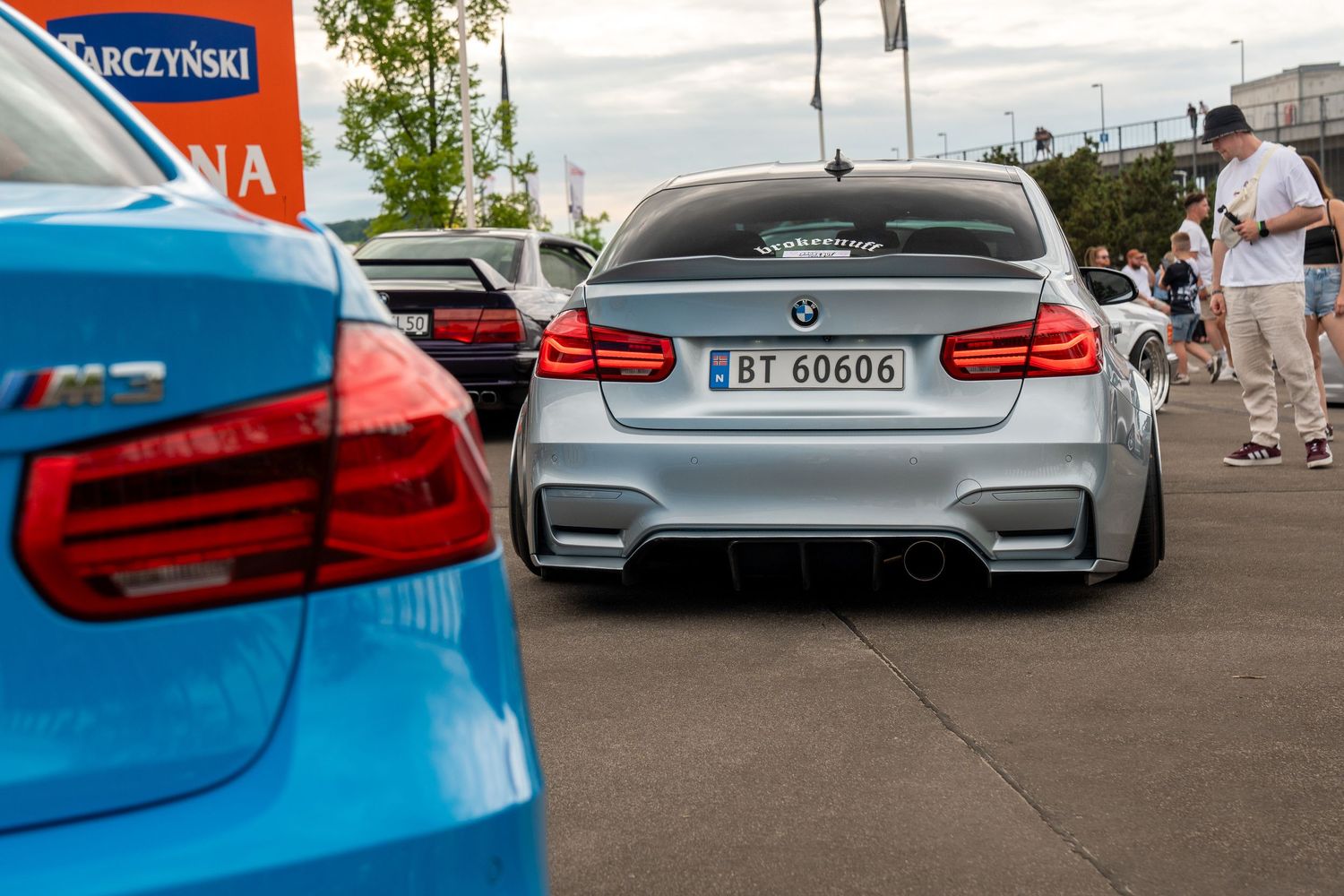Row of modified BMW M-series cars displaying various custom modifications at an auto show.