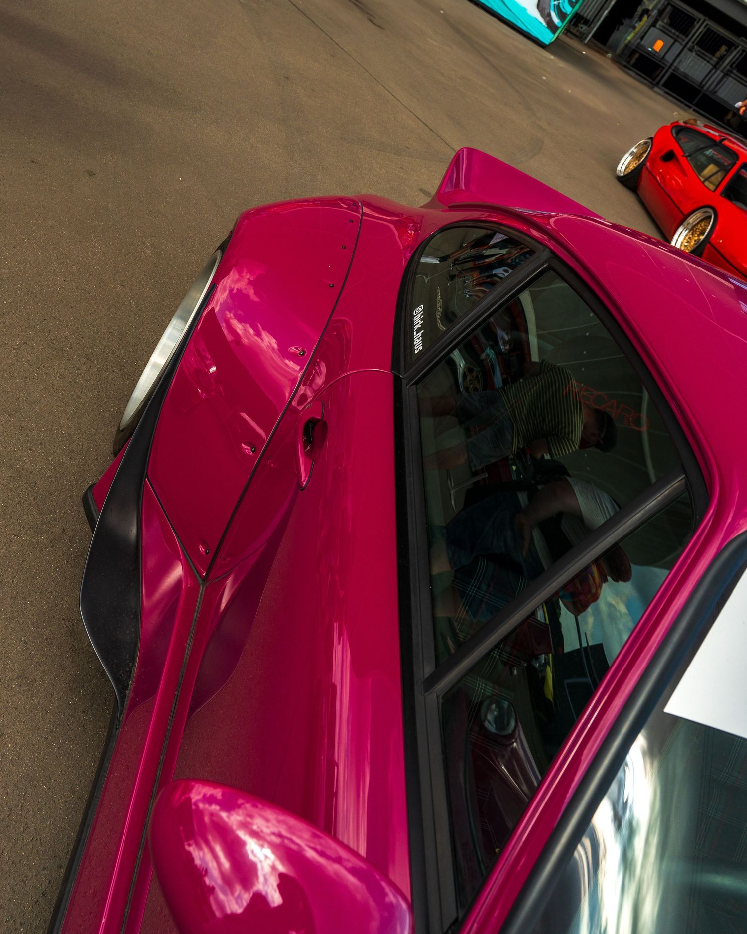 A bright pink modified car showcasing its sleek roofline and custom modifications.