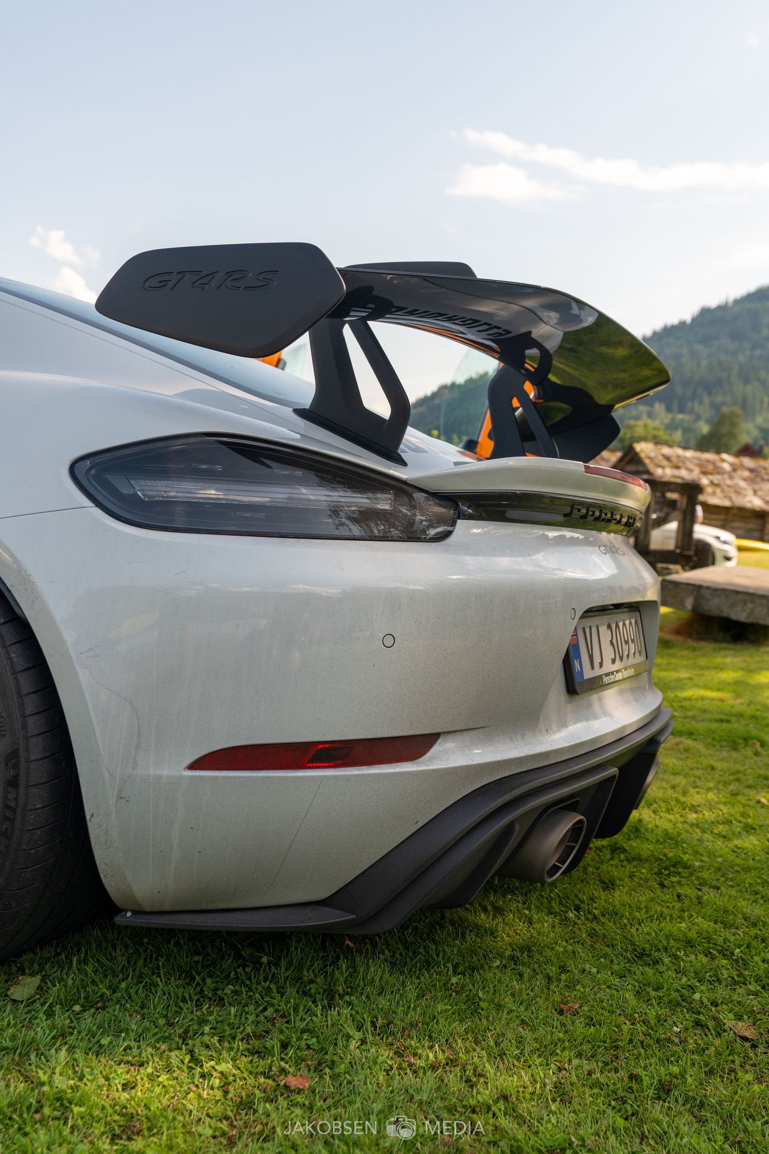Close-up view of the rear bumper and diffuser of a white Tesla Model S performance vehicle on grass.