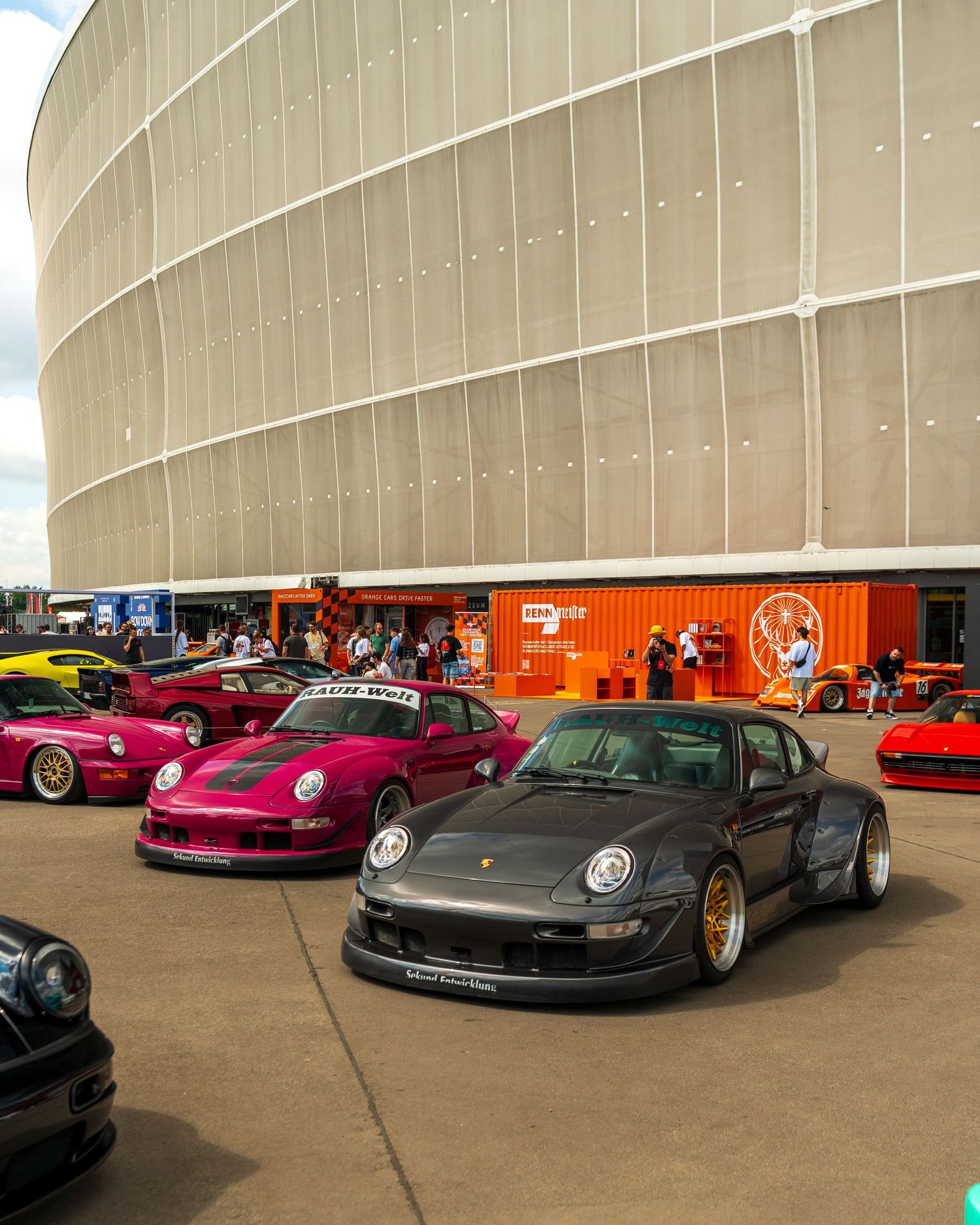 Collection of modified Porsche 911s in various colors parked at a car meet.