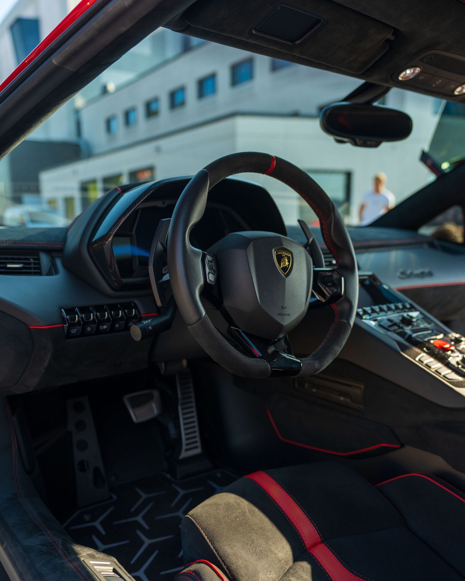 Luxurious sports car interior featuring red accents and carbon fiber trim details.