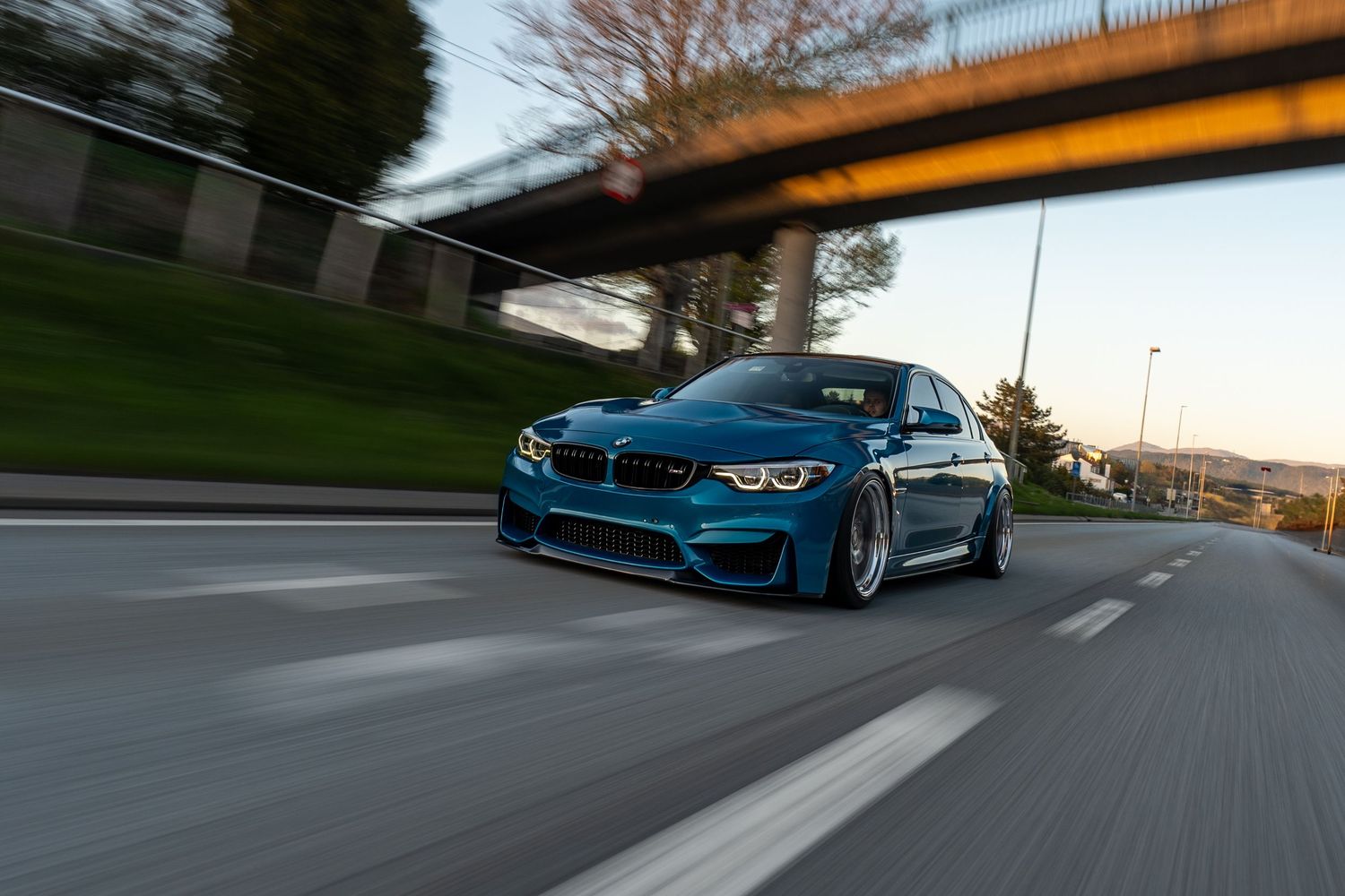 Blue BMW M4 speeding on highway with motion blur effect.