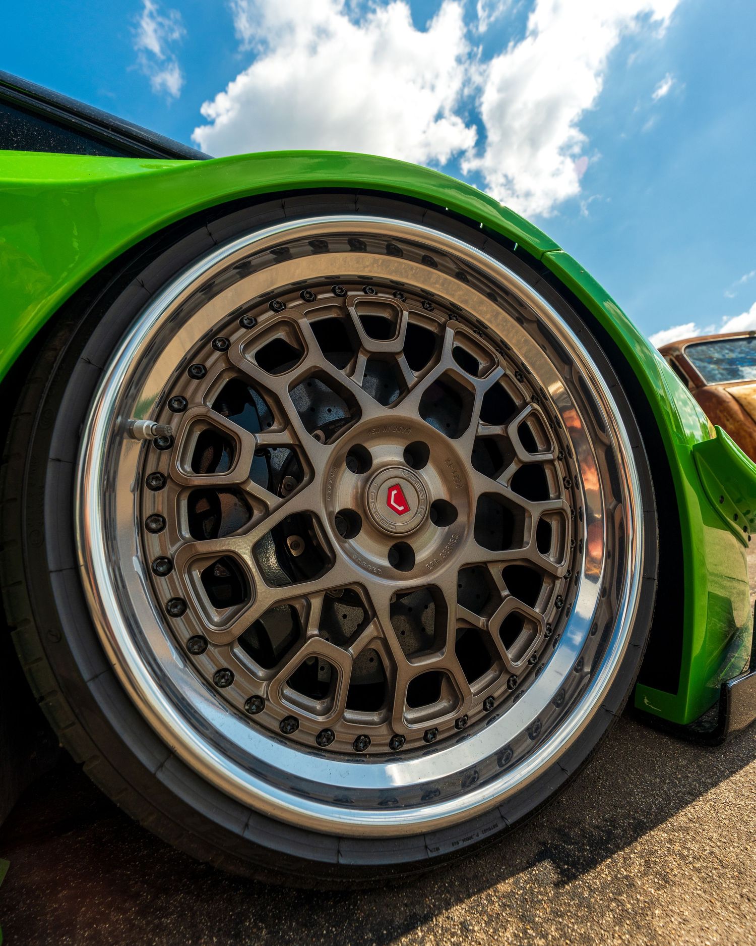 Lime green car featuring a bronze mesh-pattern wheel with polished lip on stretched tires.