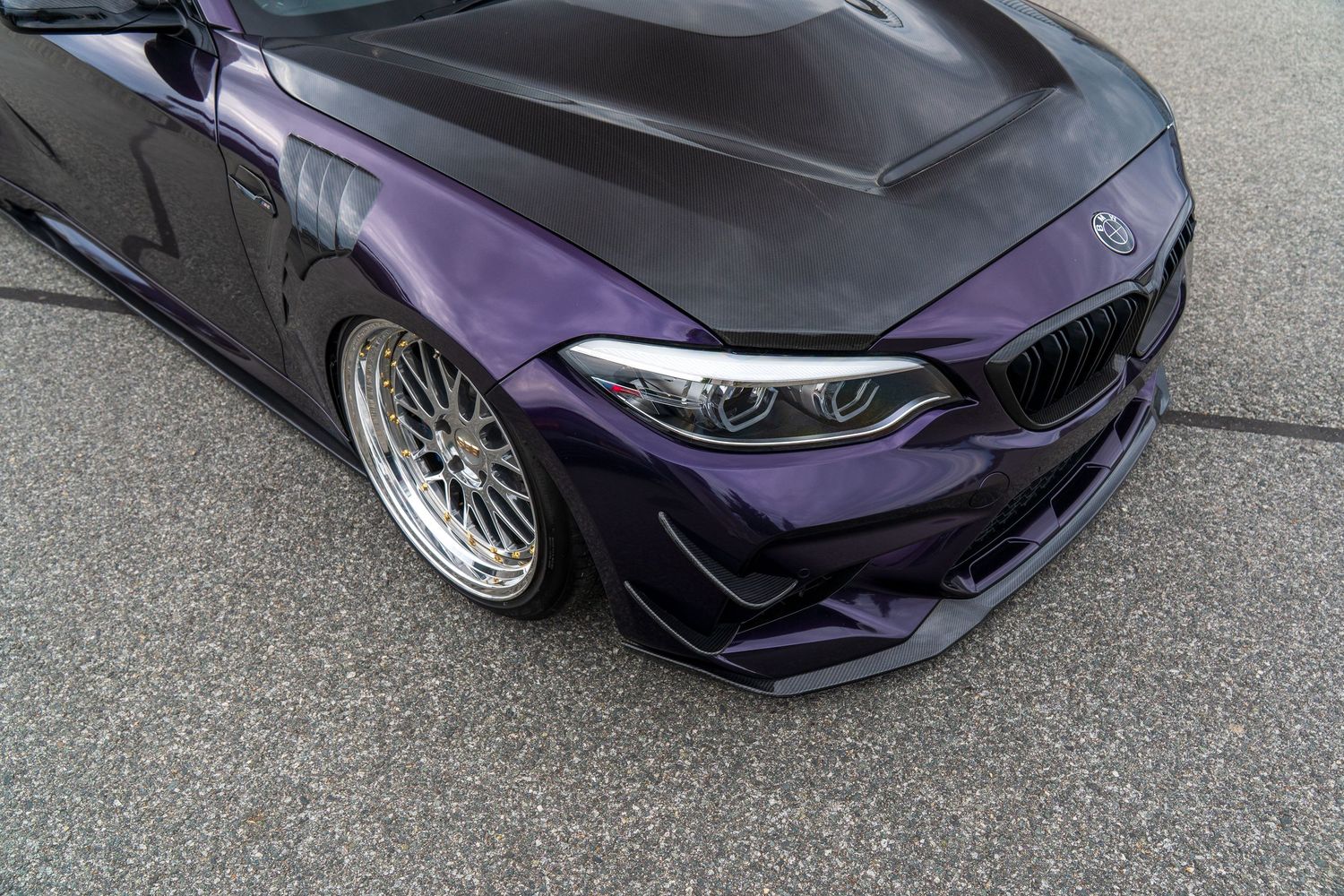 Purple modified sports car with aggressive body kit and custom wheels at car show.