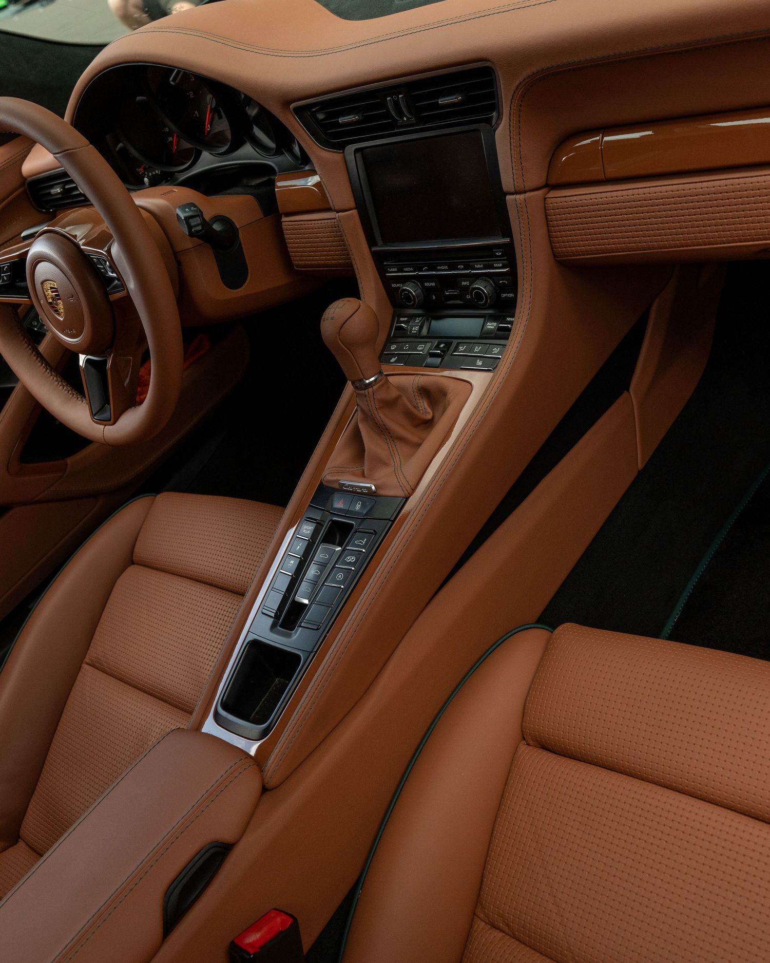 Luxury brown leather interior of a Porsche showing the center console and dashboard.