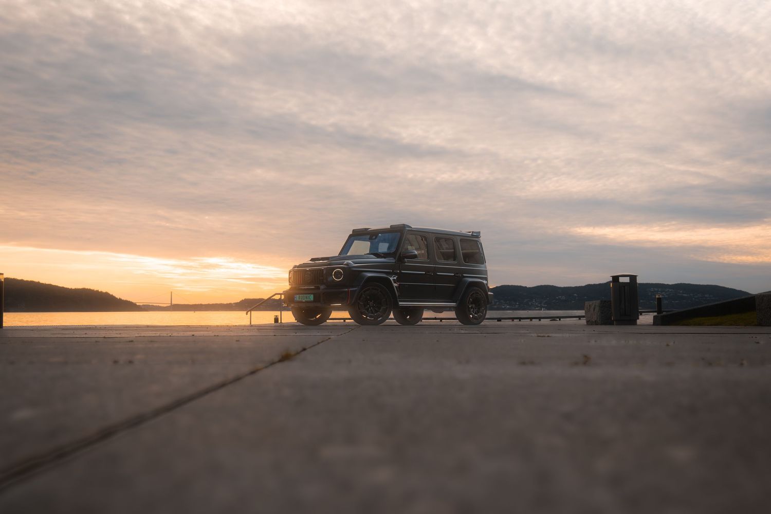 Silhouetted pickup truck parked by the ocean during a dramatic coastal sunset.
