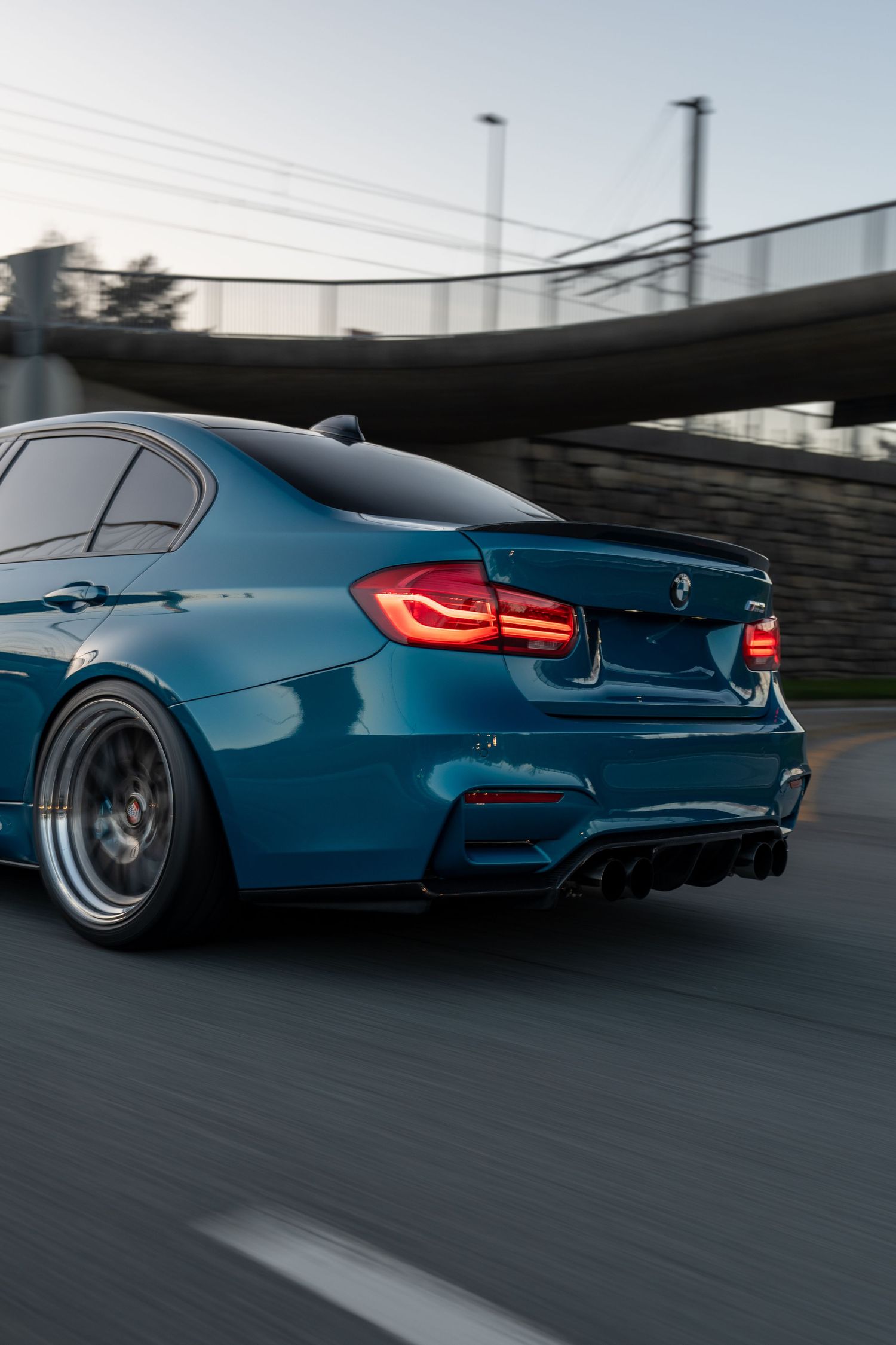 Modified blue BMW M3 shows off aggressive rear stance with wide wheels and lowered suspension.