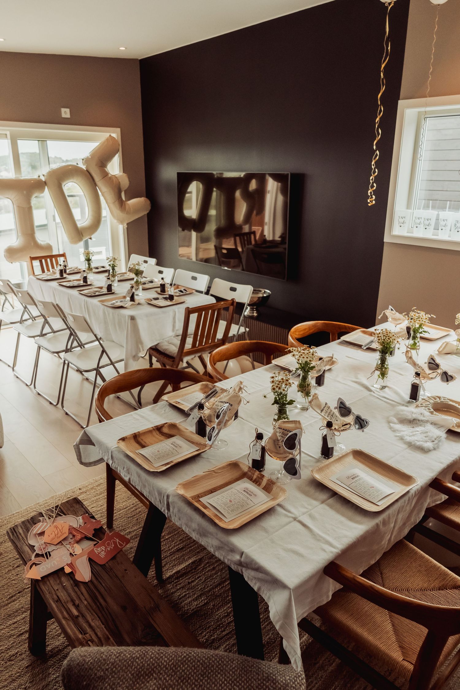 Dining room setup with balloon decorations and two long tables for a celebration.