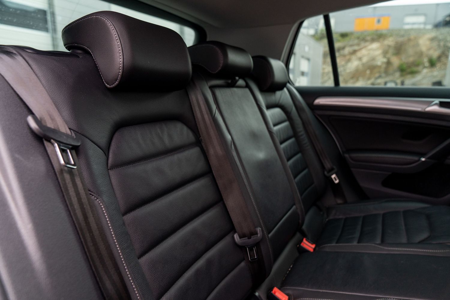 Rear seating area of an upscale vehicle with black leather upholstery and center armrest.