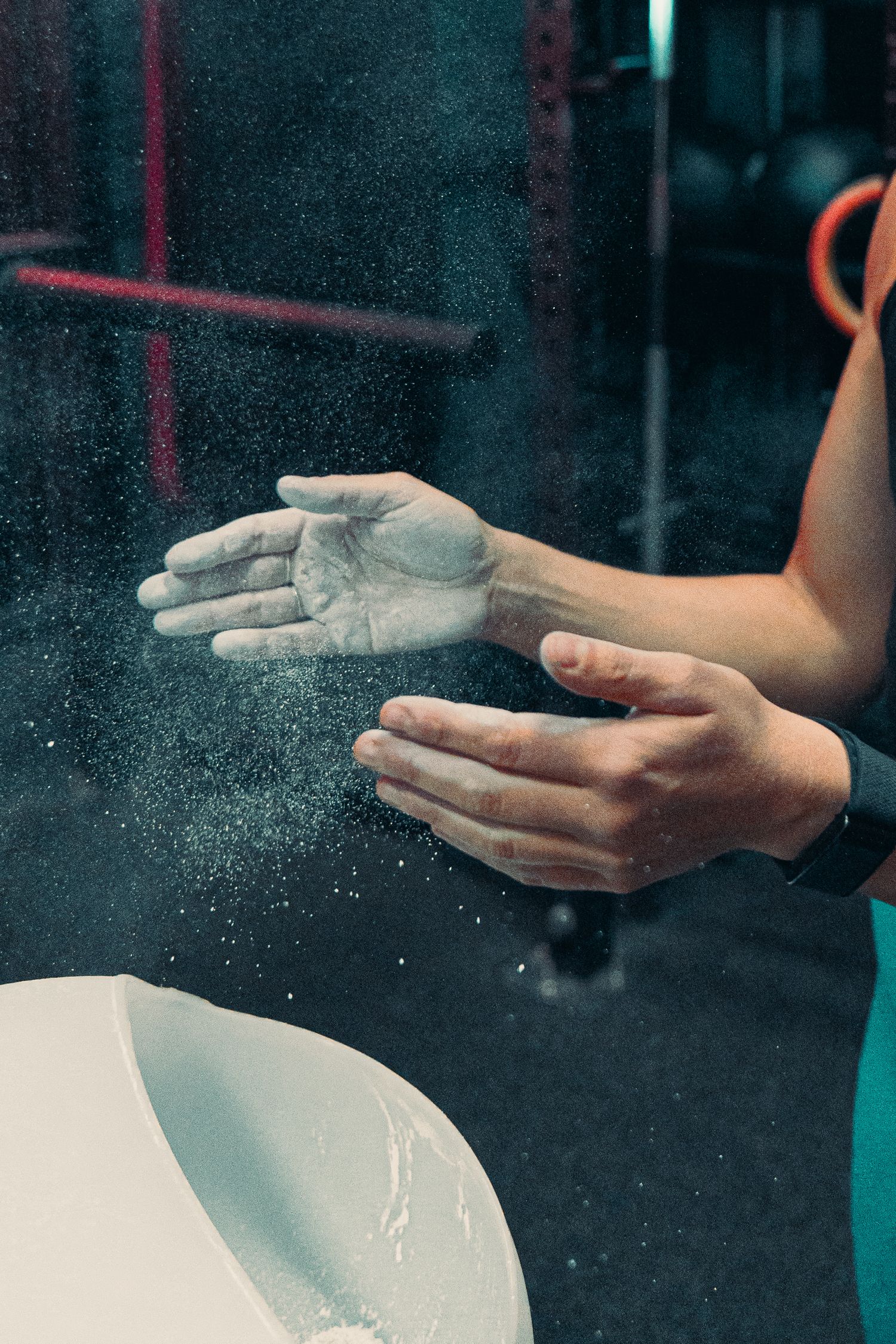 Hands clapping with white chalk powder creating a dusty cloud effect in dark lighting.