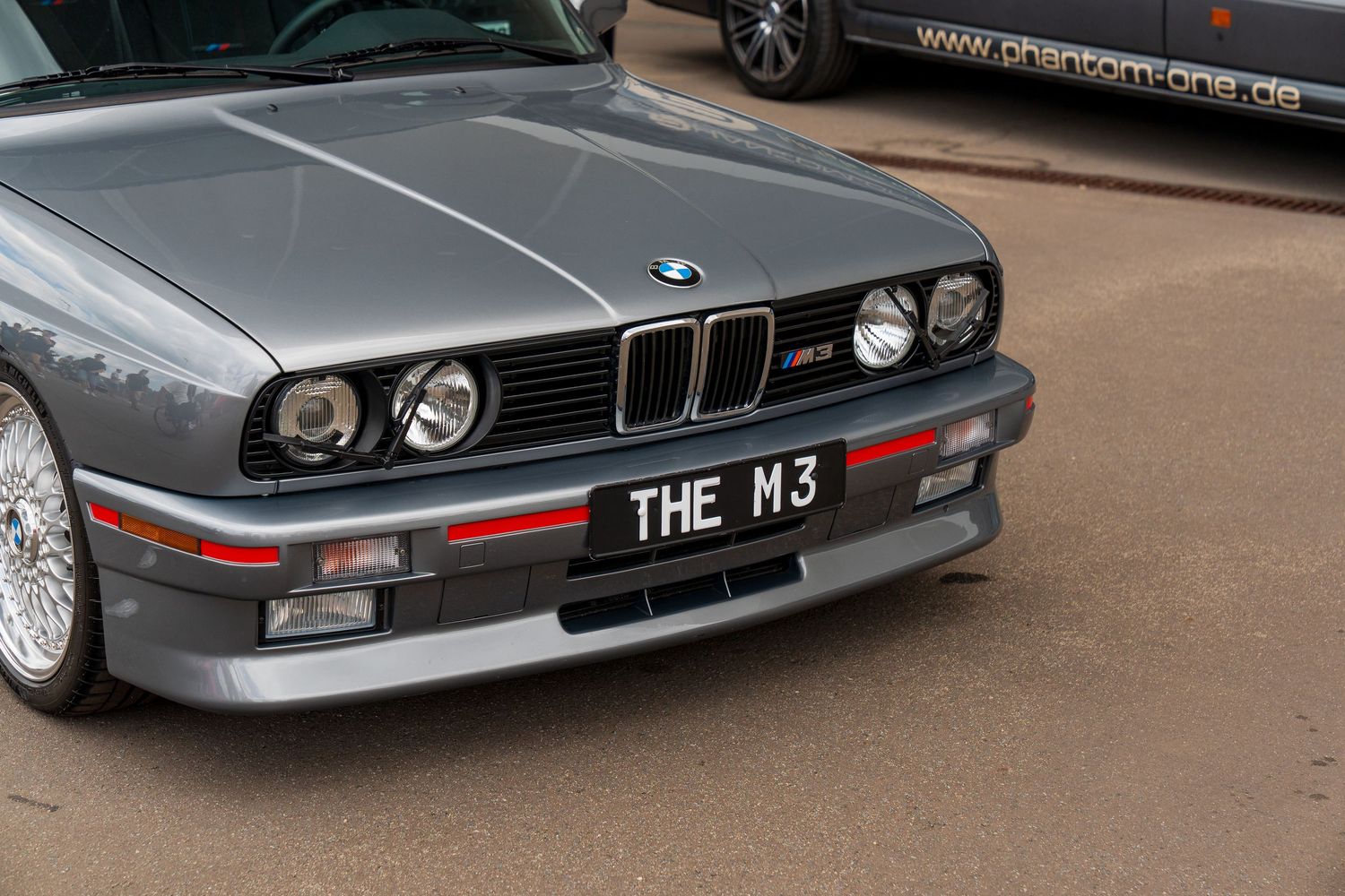 Front view of classic BMW M3 with retro headlights and custom front lip spoiler.