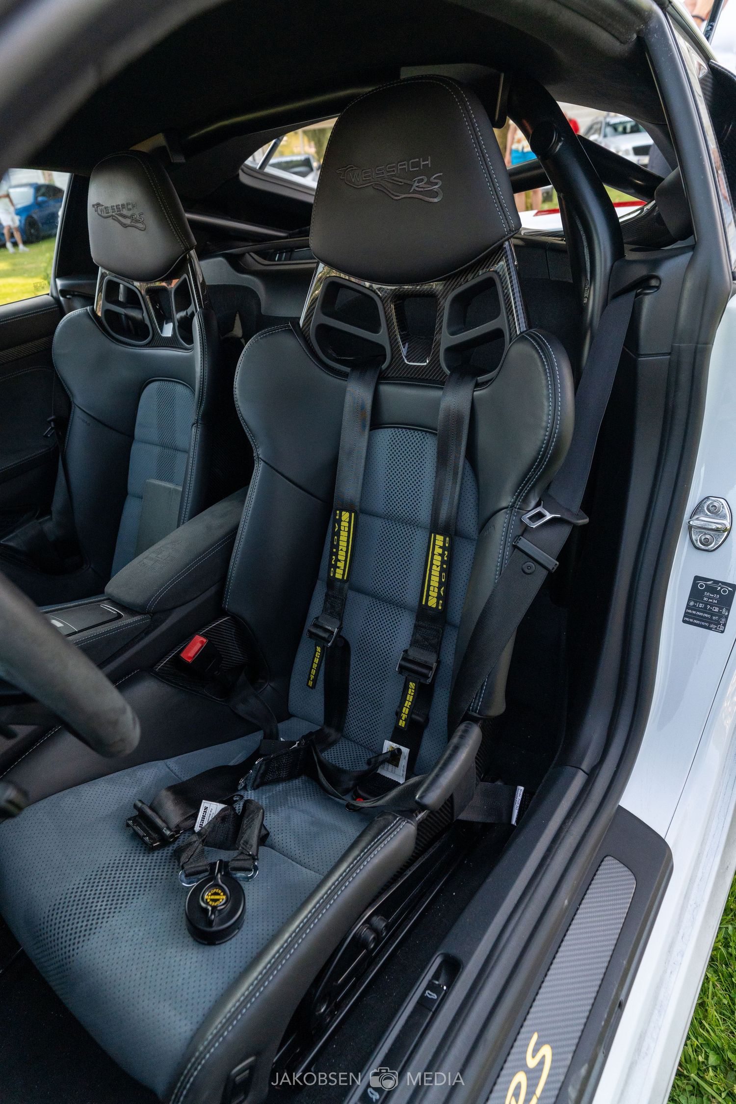 Racing bucket seats with safety harnesses inside modern sports car interior.