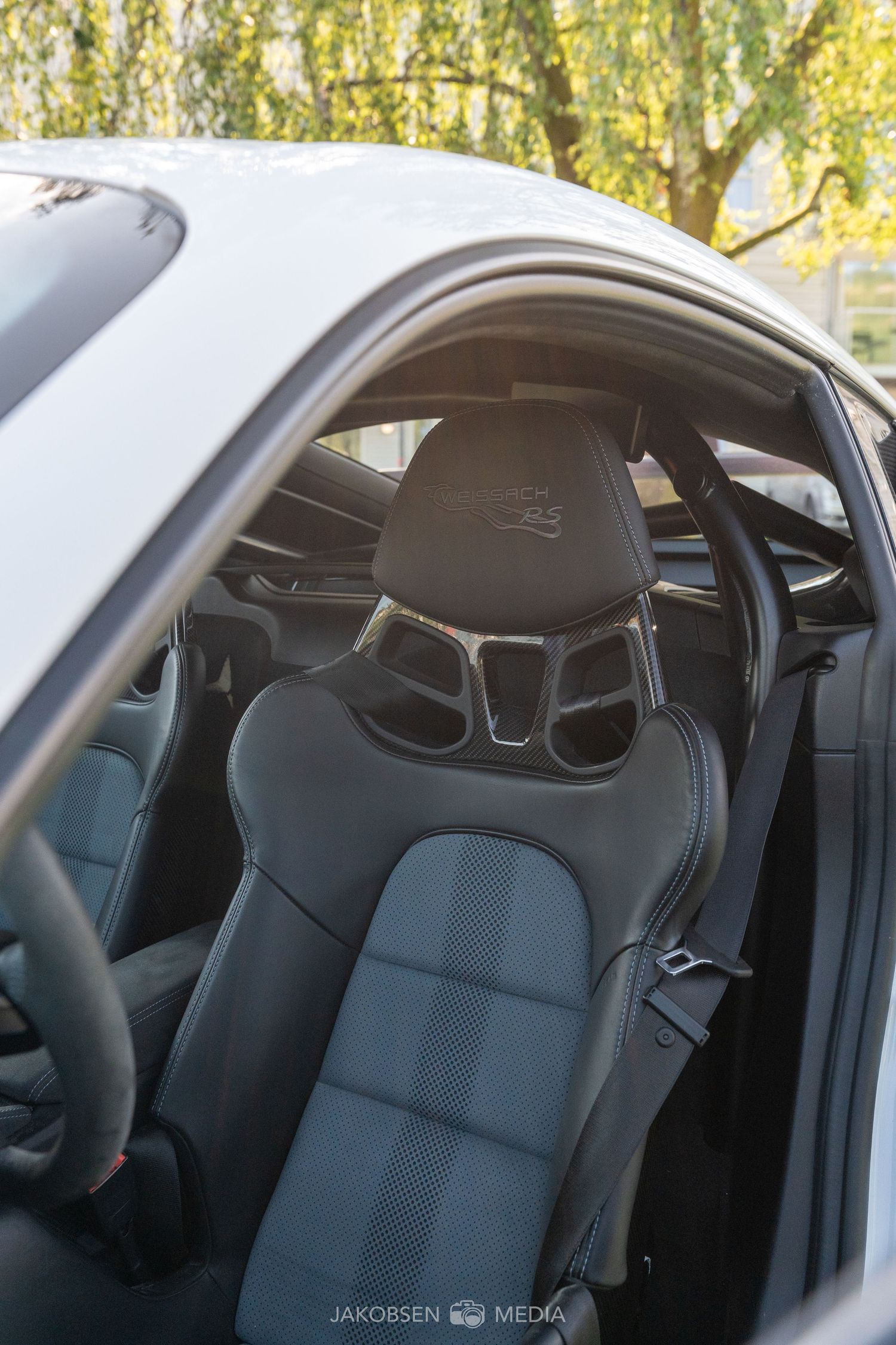Close-up view of black sporty racing seats installed in a vehicle's interior with natural lighting through windows.