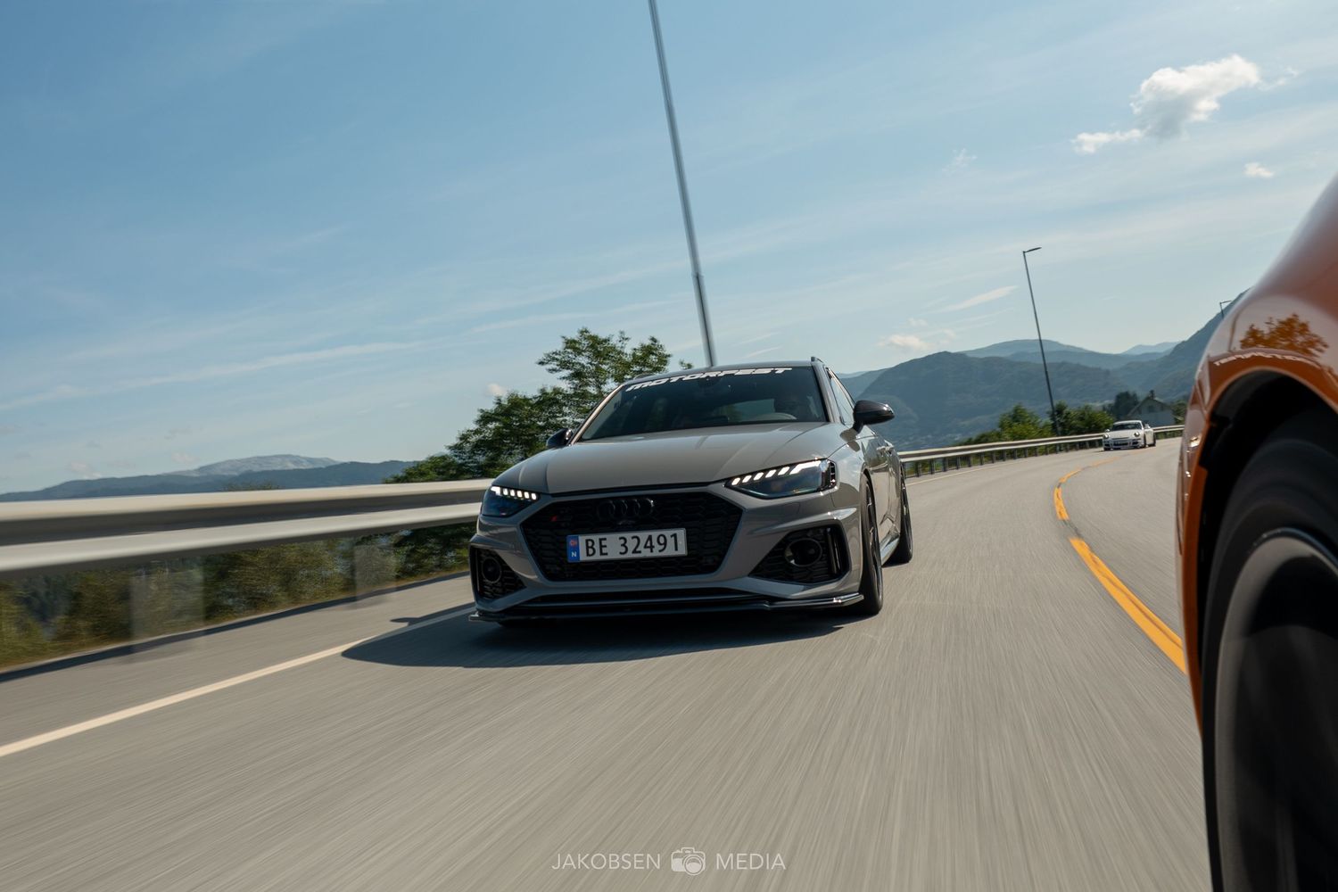 Multiple action shots of sports cars driving on an open highway with mountains visible in the distance.